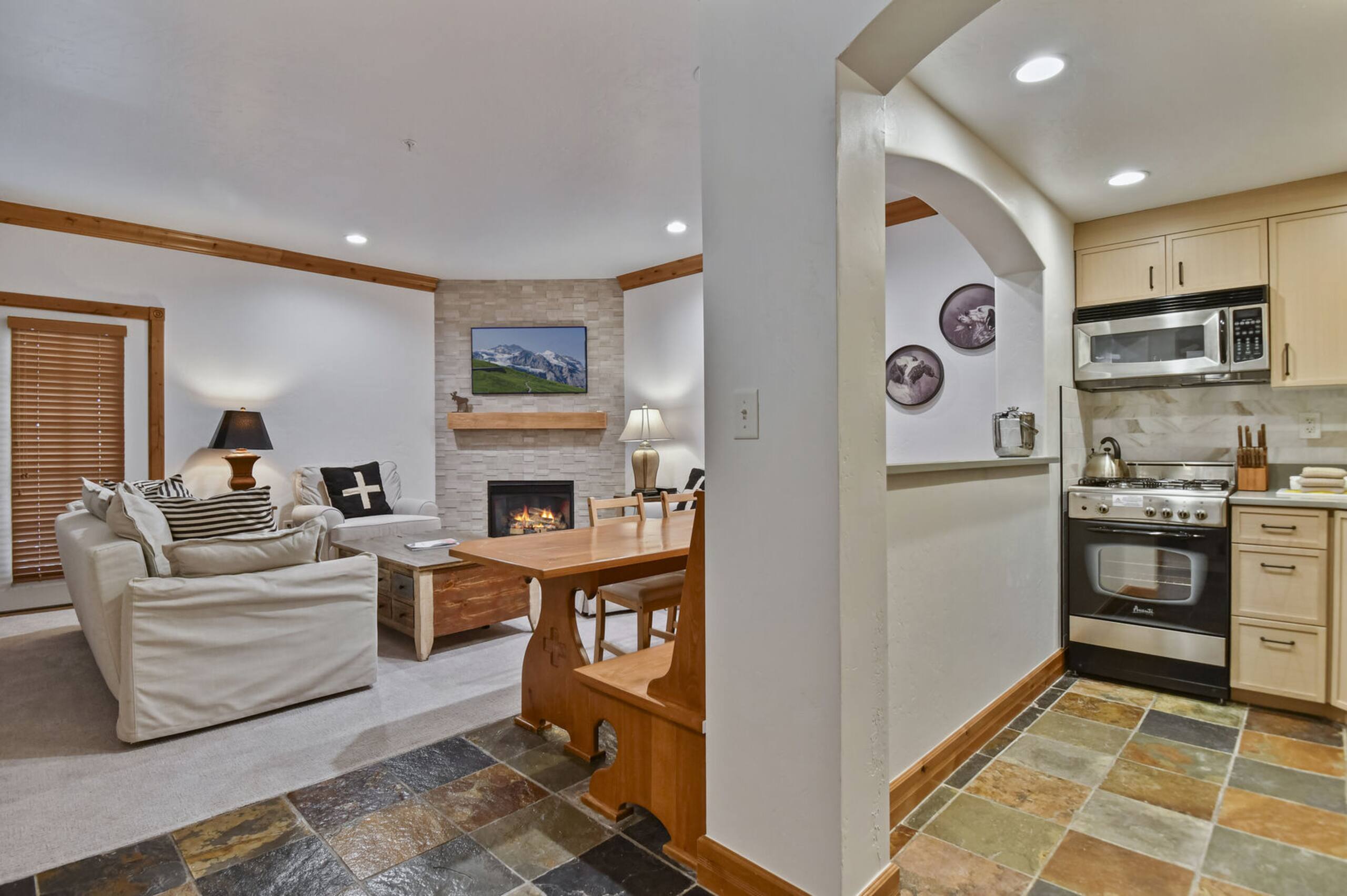 Living area featuring a stone-clad fireplace with a wood mantel, exposed wood ceiling beams, and recessed lighting