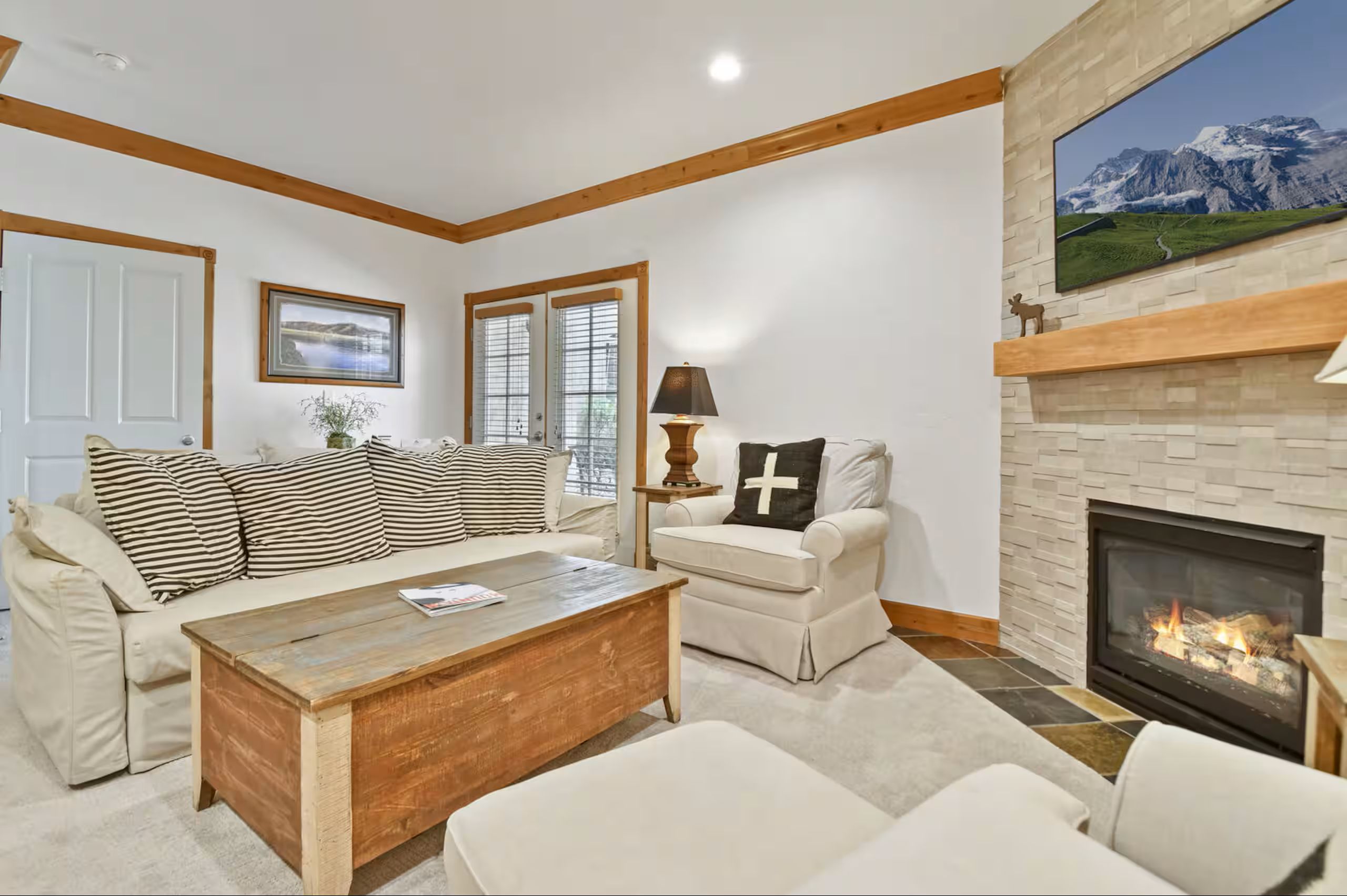Living area featuring a floor-to-ceiling stone-faced fireplace with a natural wood mantel and hearth
