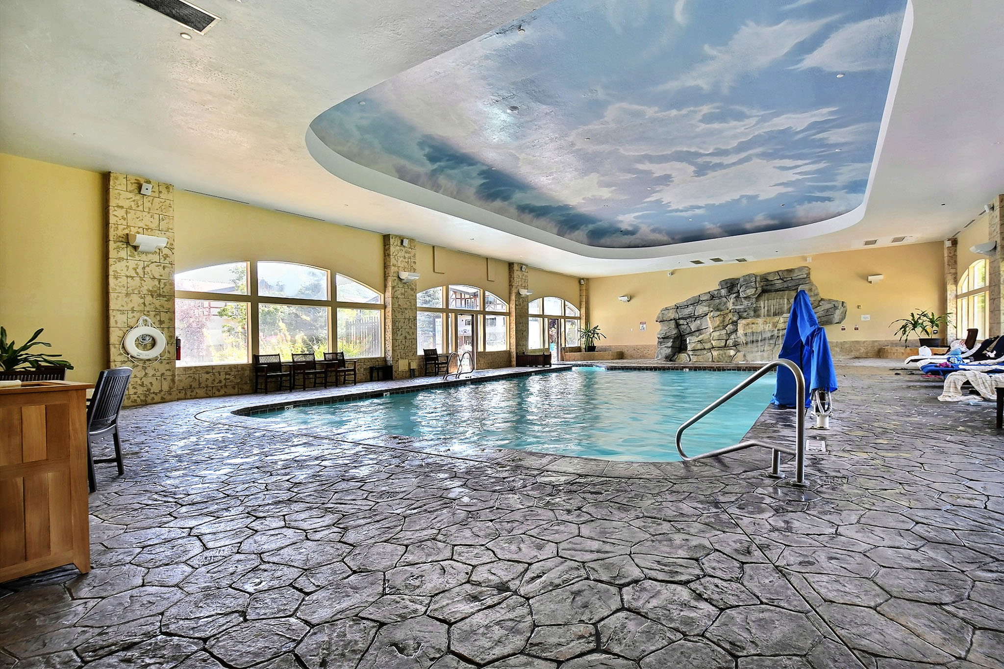 Indoor swimming pool featuring a decorative rock waterfall