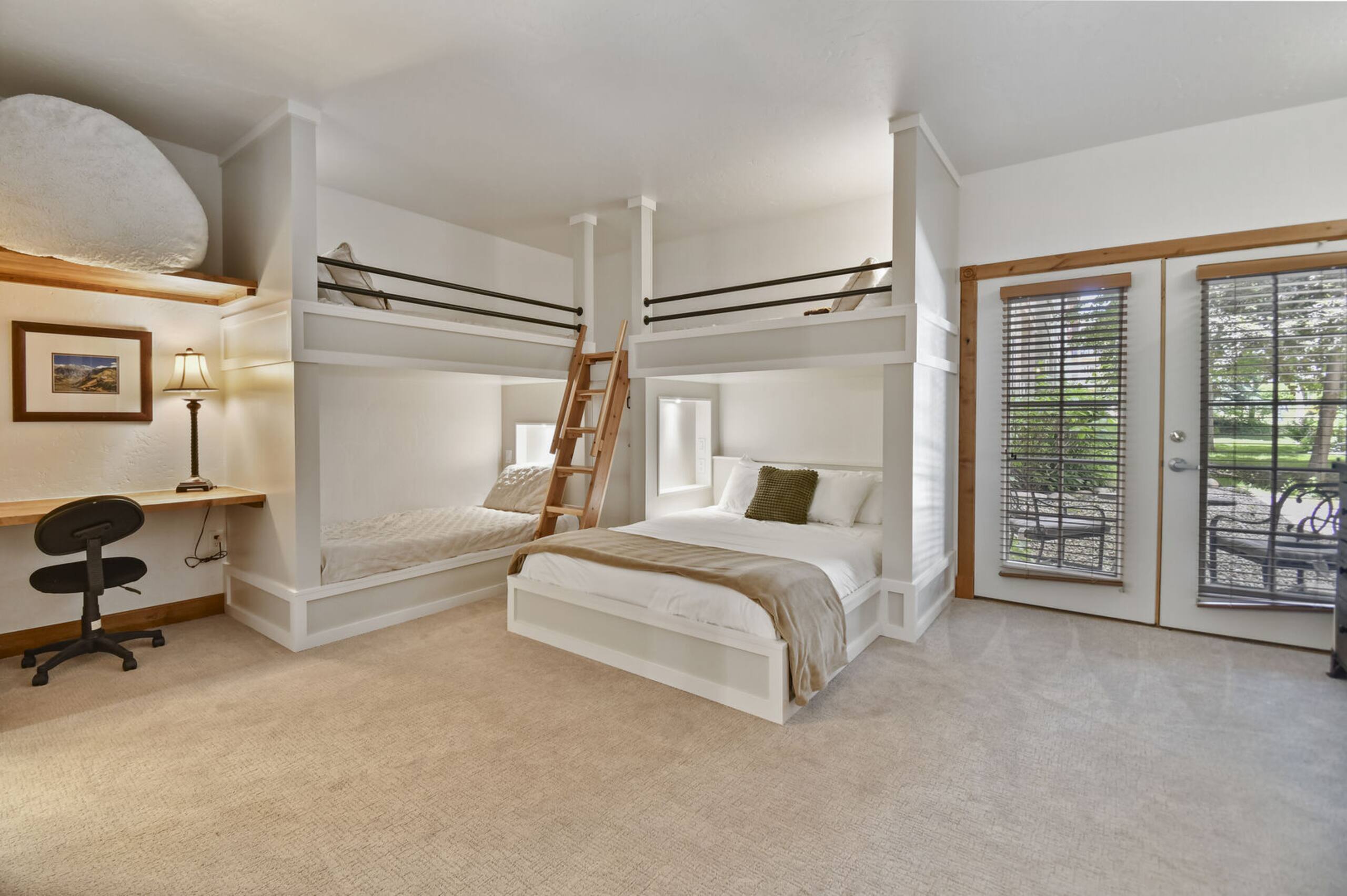 Built-in bunk beds with integrated ladders, neutral carpeting, and a floating desk with shelving