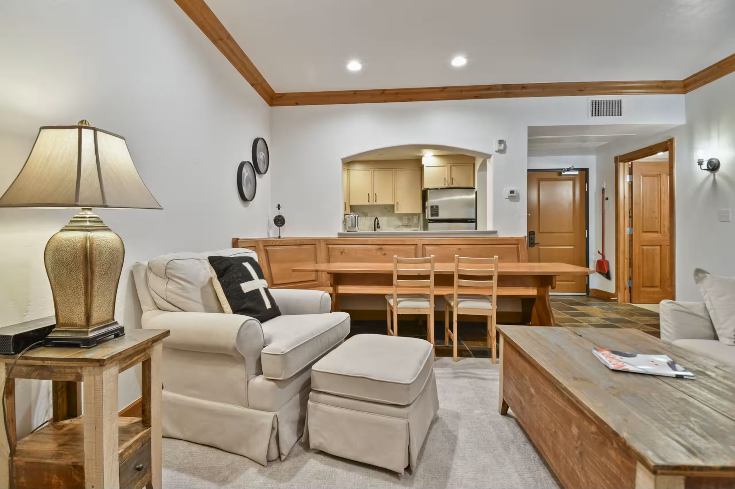 Open concept living area featuring a built-in dining bench, wood-finish beams, recessed lighting, and a kitchen pass-through with an arched opening