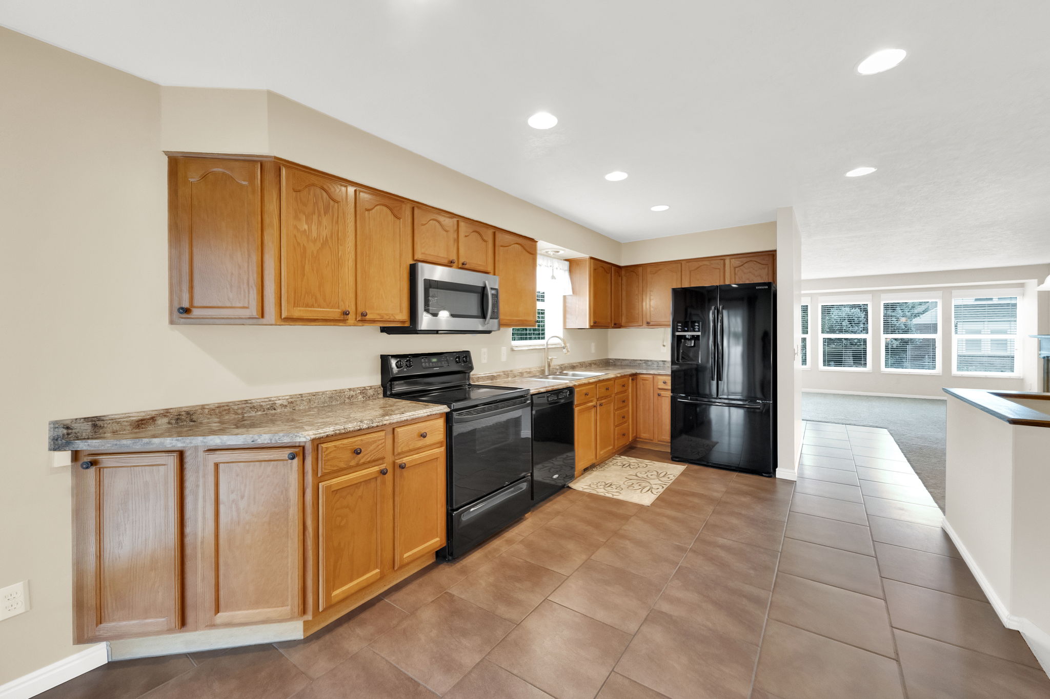 Kitchen featuring wood cabinetry, stone-finish countertops, and black appliances