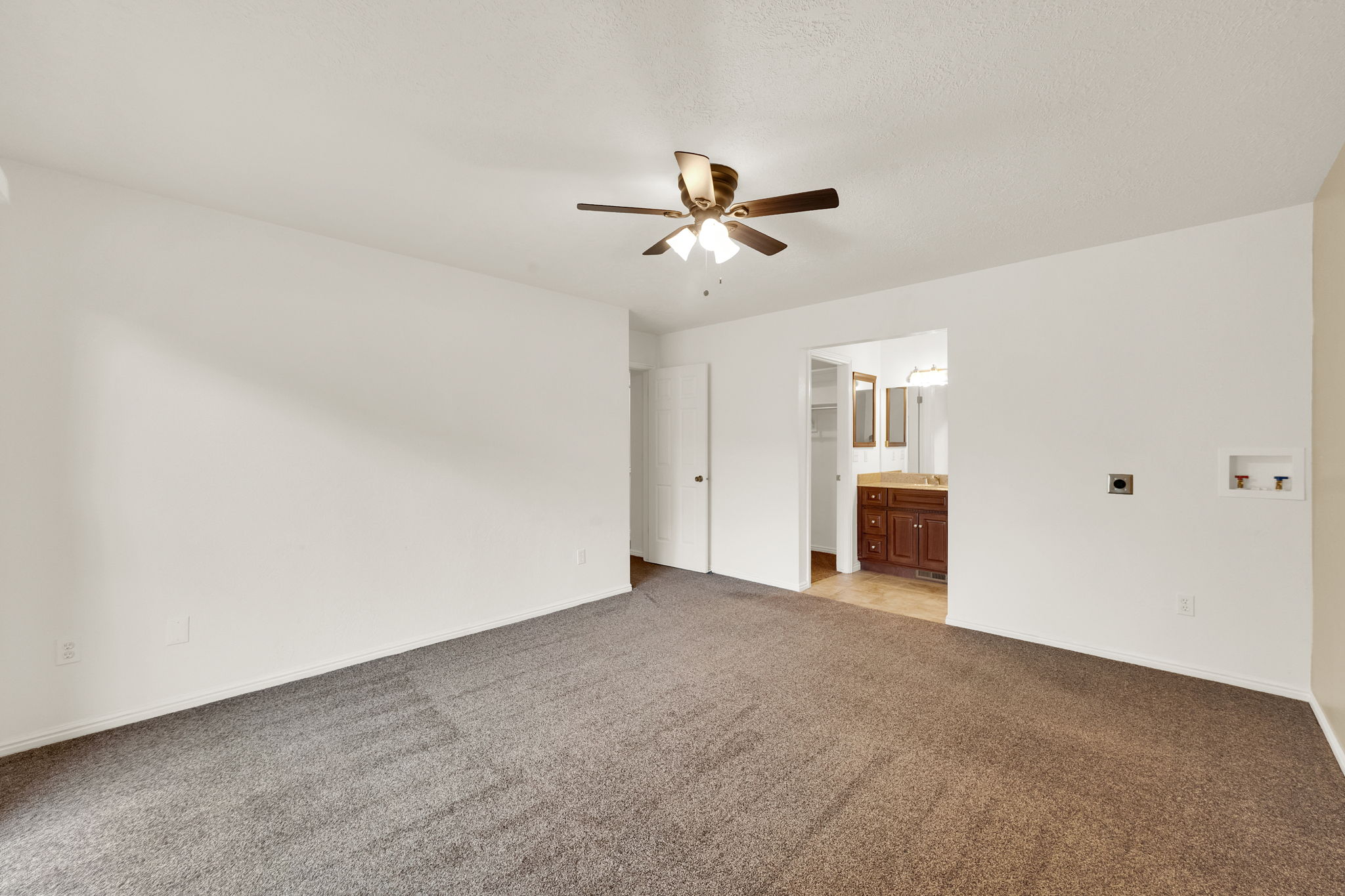 Spacious carpeted room featuring a ceiling fan with integrated lighting