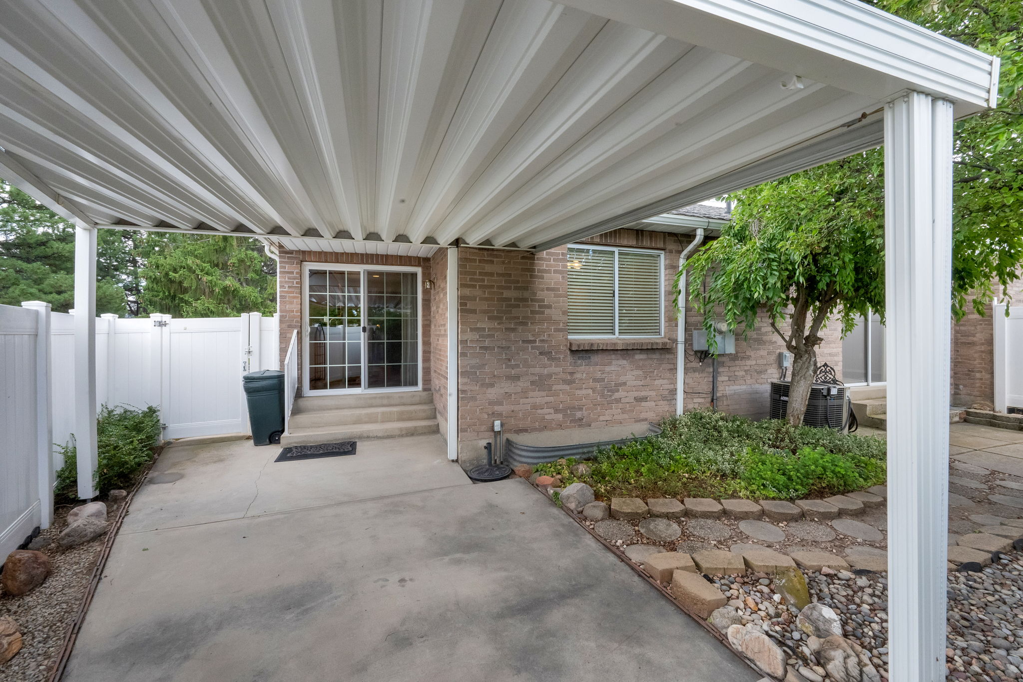 Covered concrete patio featuring a white slatted ceiling and support columns