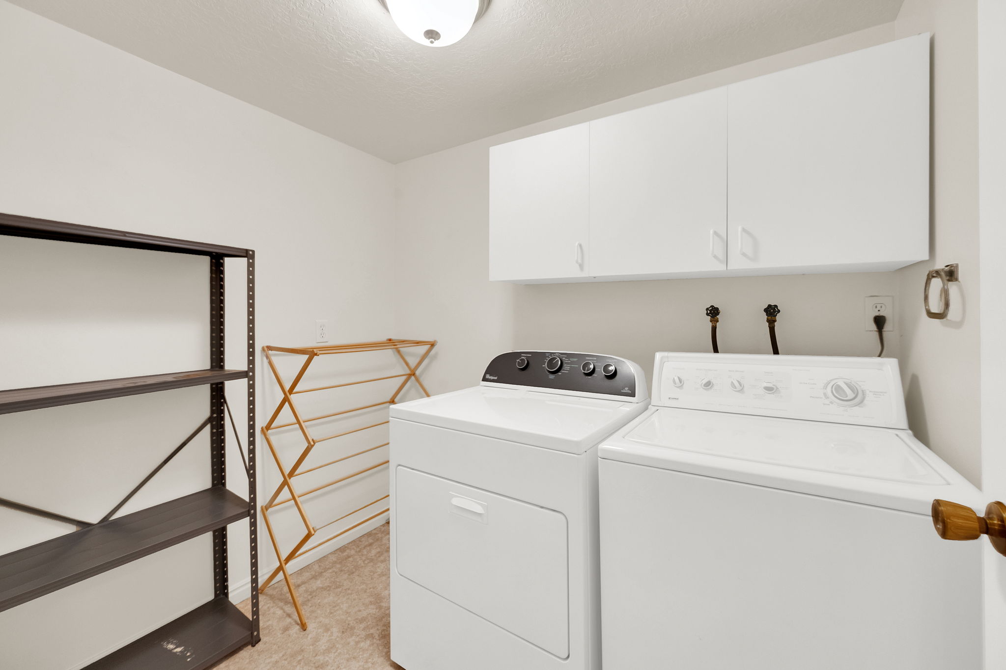 Dedicated laundry area featuring a washer and dryer, upper white cabinetry, and carpet flooring