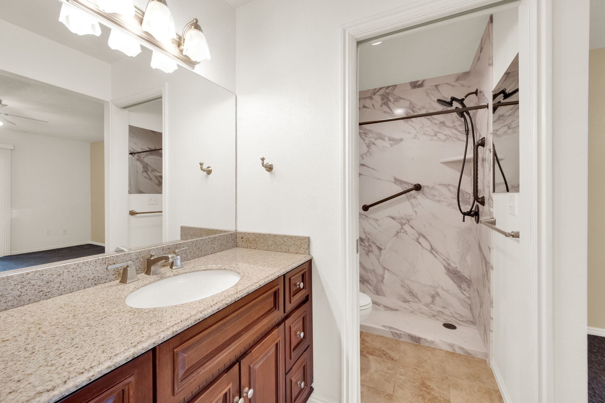 Bathroom vanity featuring a light granite countertop, undermount sink, and wood-finish cabinetry
