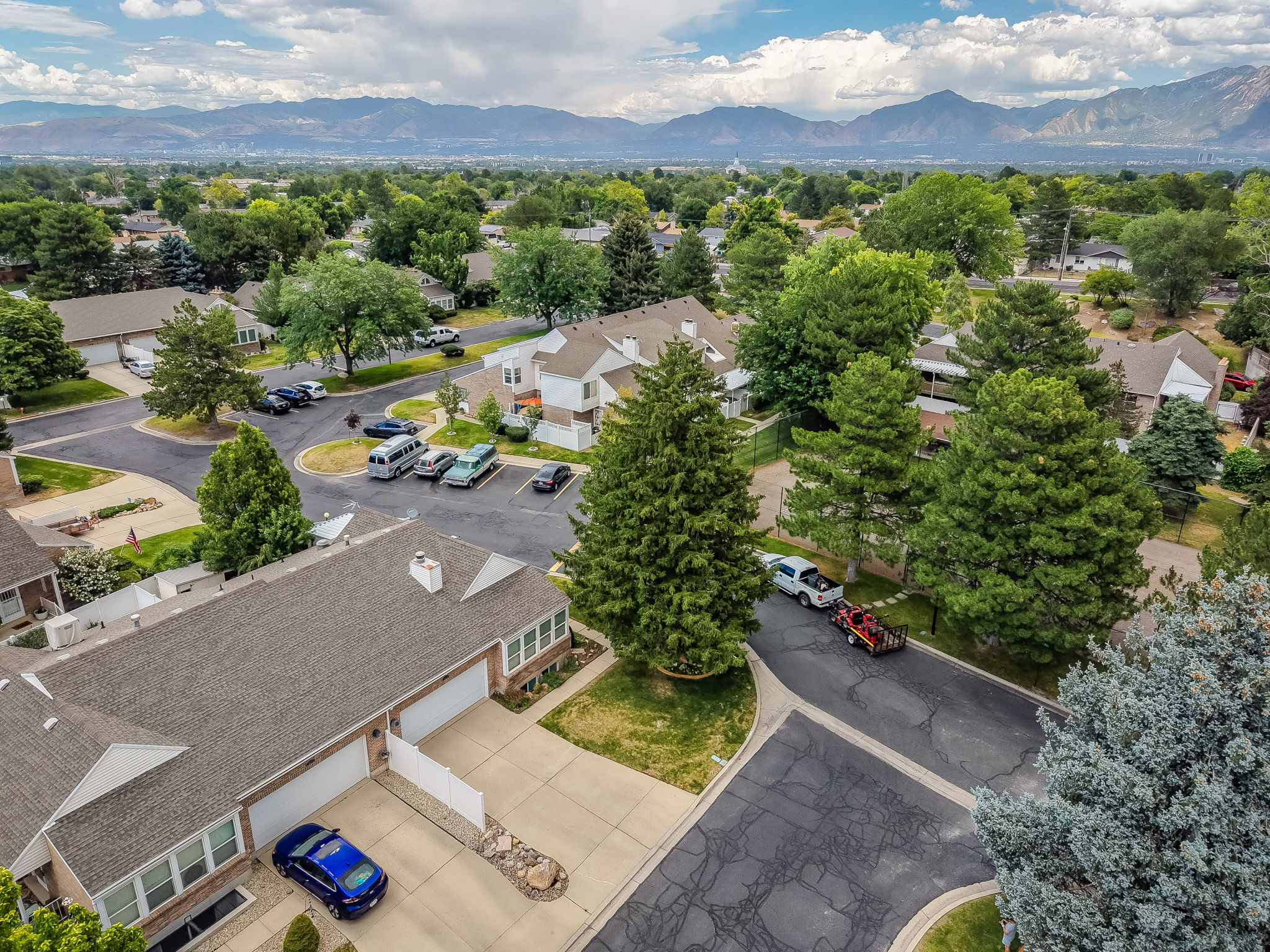 Aerial perspective showcasing a residential community with abundant mature trees and mountain scenery