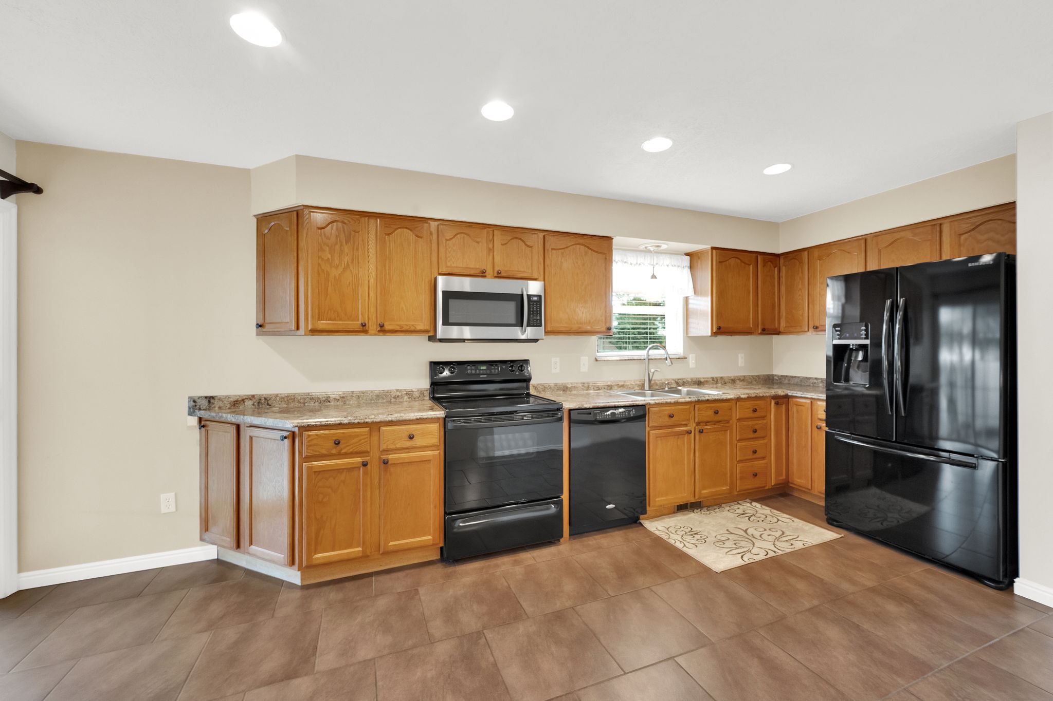 Kitchen featuring wood cabinetry, stone-look countertops, and recessed lighting