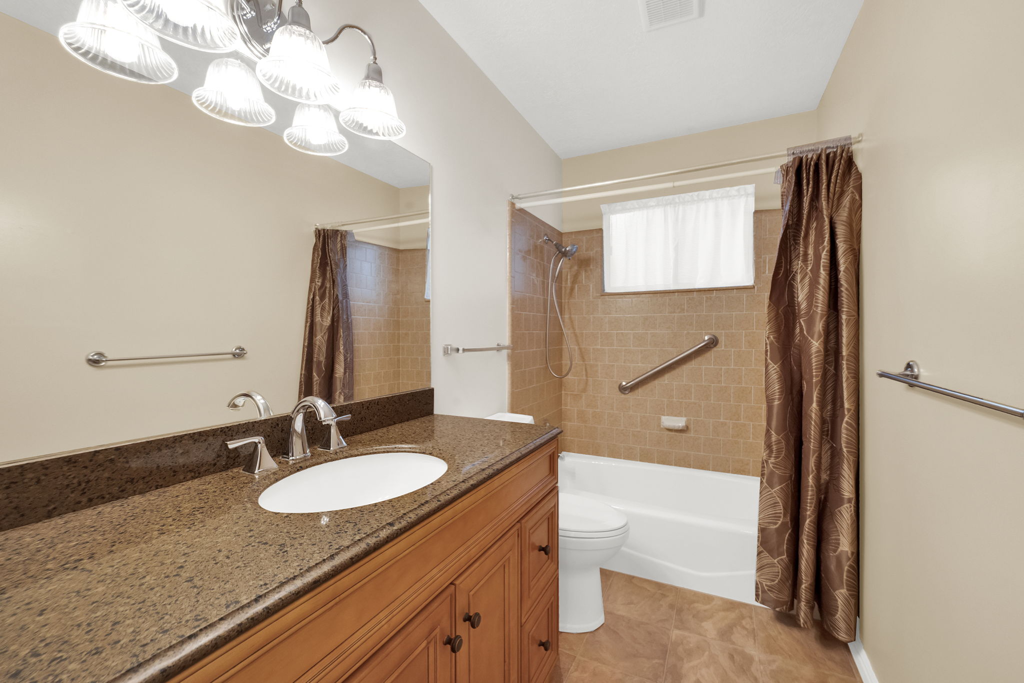 Bathroom featuring a wood vanity with an integrated sink, polished chrome faucet, and dark speckled countertop