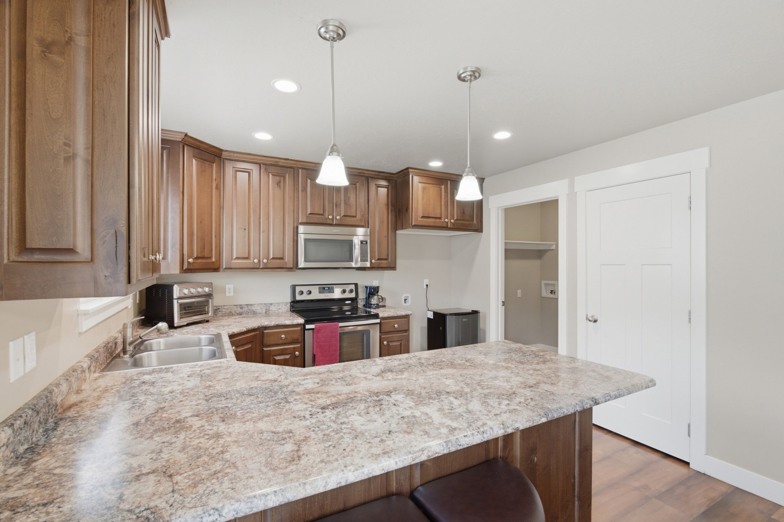 Kitchen featuring wood cabinetry, stainless steel appliances, a double basin sink, and pendant lighting