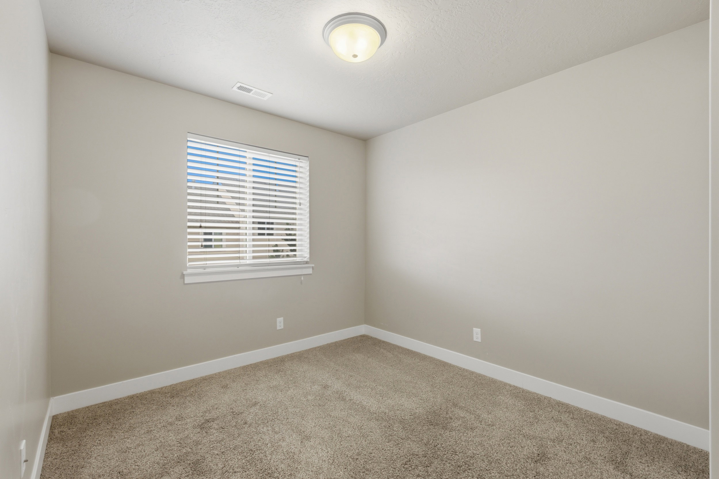 Room featuring neutral-toned walls, white trim, and a window with blinds