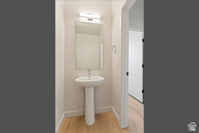 Pedestal sink with chrome faucet, illuminated by a modern light fixture
