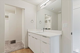 Bathroom vanity with a white countertop and integrated sink, chrome faucet, and expansive wall mirror