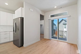 Open-concept living space featuring wood-finish flooring, recessed lighting, and a sliding glass door leading to a private balcony