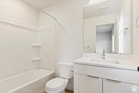 Bathroom featuring a white vanity with integrated sink, a large wall-mounted mirror, and a white toilet