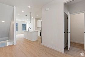 Open-concept living space featuring wood-finish flooring, recessed lighting, and a modern kitchen island with pendant lighting and a gooseneck faucet
