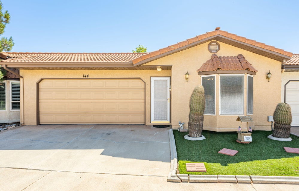Spanish-style residence featuring a tile roof, stucco exterior, integrated two-car garage, and a prominent bay window