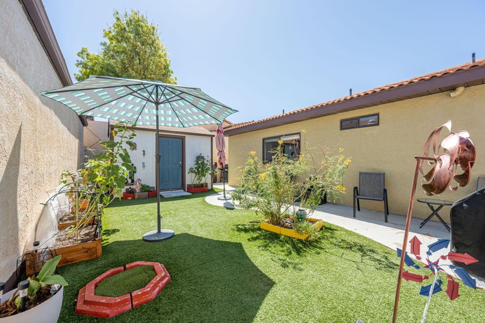 Private backyard featuring artificial turf, a concrete patio, and a stucco exterior with a terra cotta tile roof