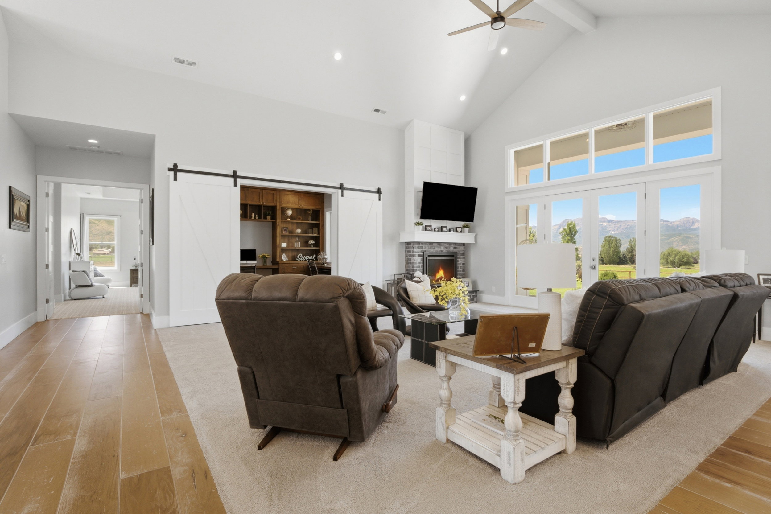 Vaulted ceilings highlight this living space, featuring a corner fireplace with a dark tile surround and a crisp white mantel