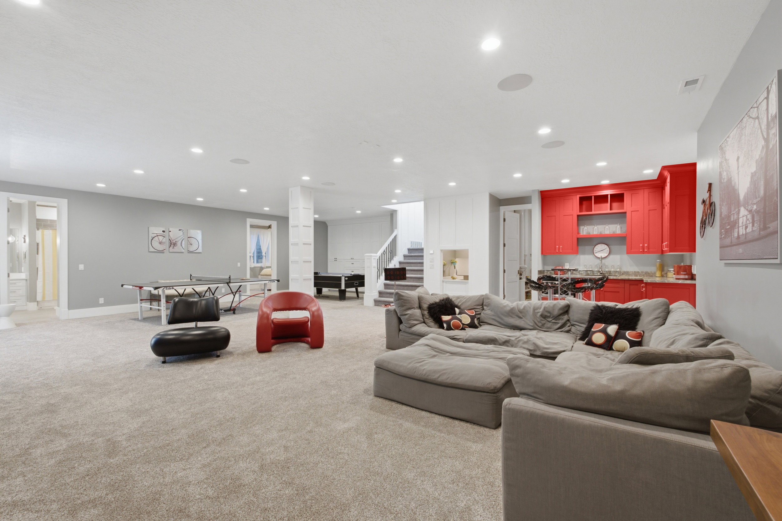 Spacious finished lower level featuring recessed lighting, light-toned carpet flooring, a vibrant red built-in wet bar, and a built-in display niche