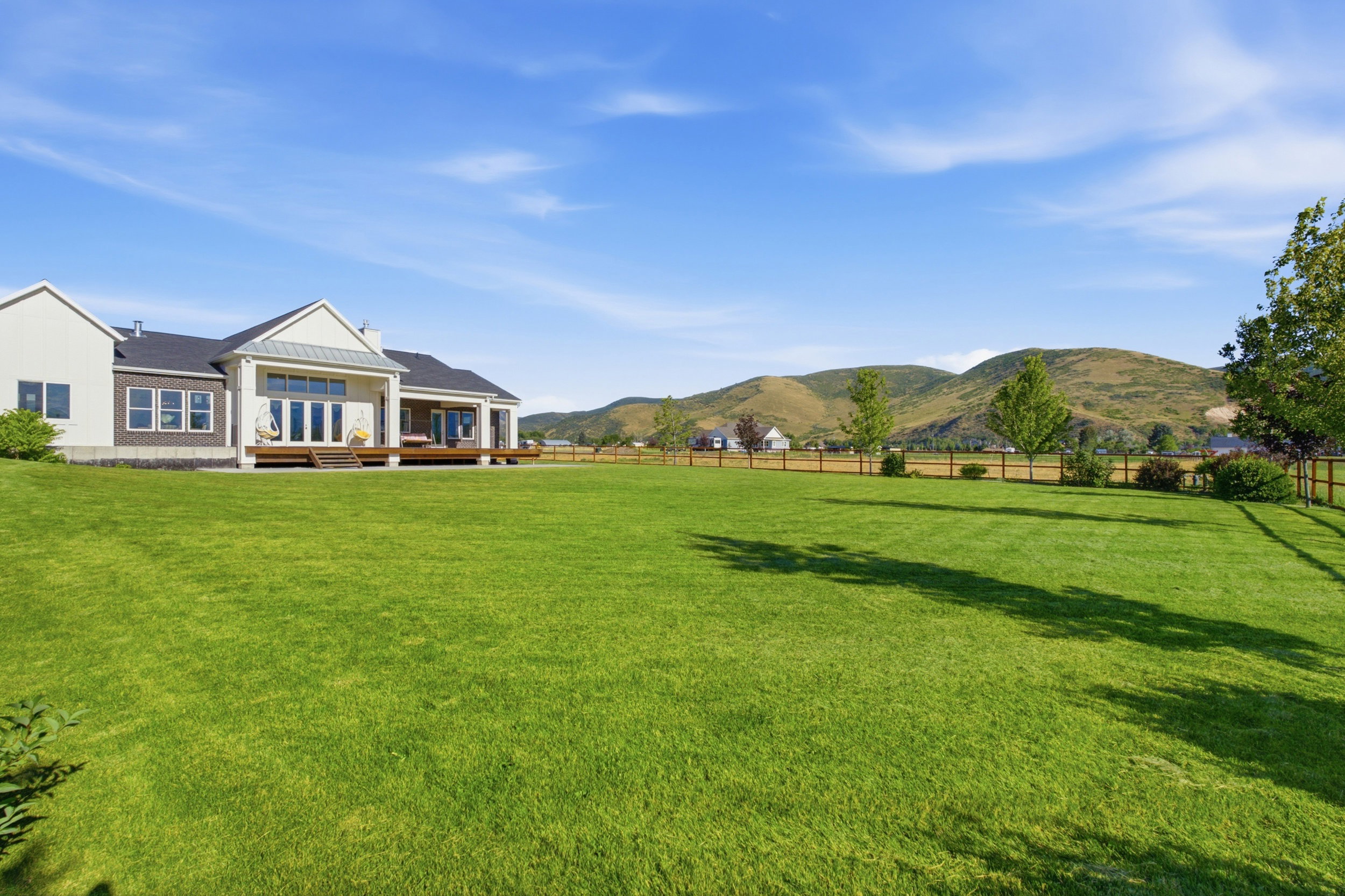 Expansive green lawn with a wooden perimeter fence and distant mountains