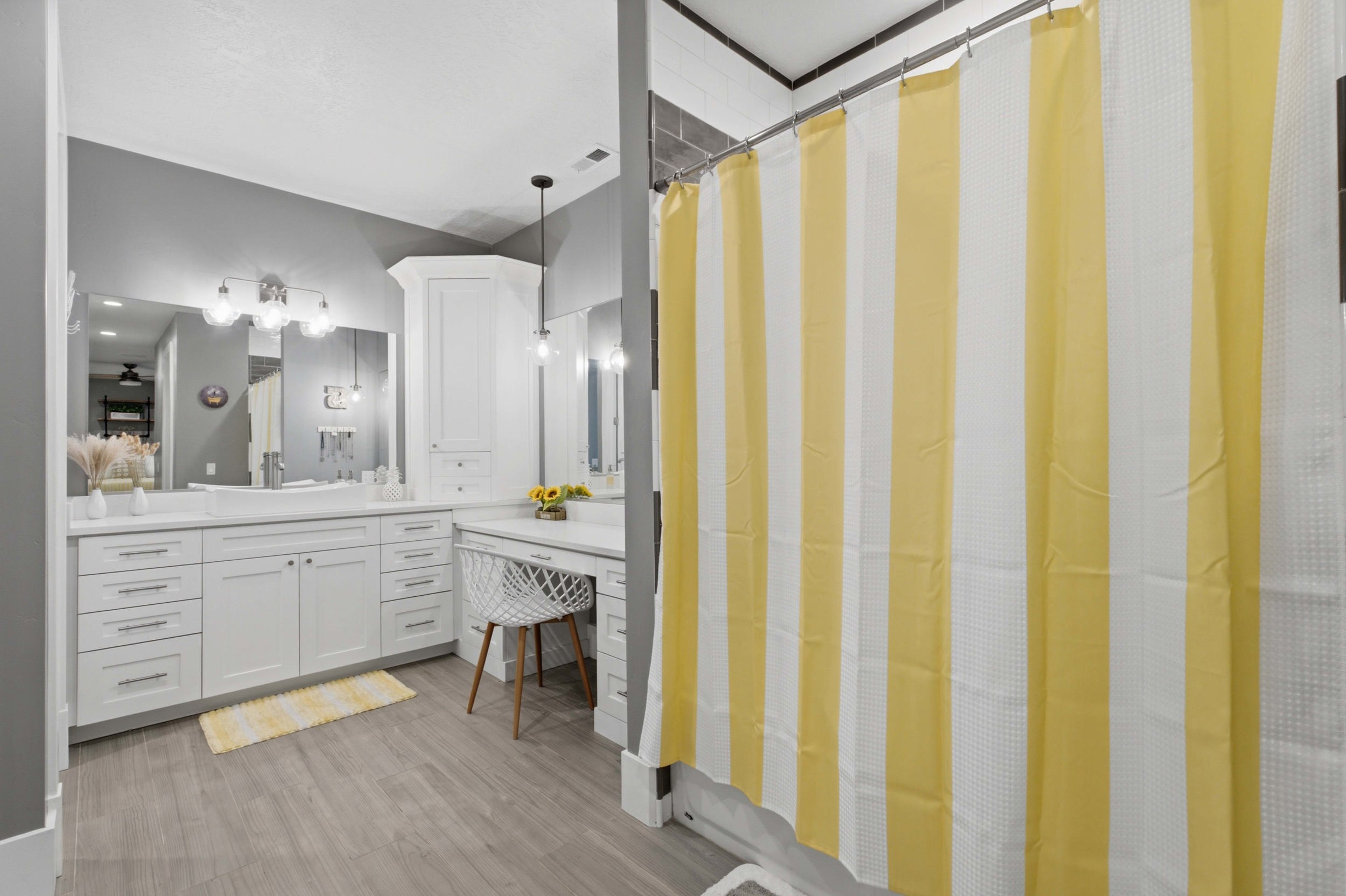 Bathroom featuring white cabinetry, wood-finish flooring, dual vanity sinks, and a built-in makeup desk