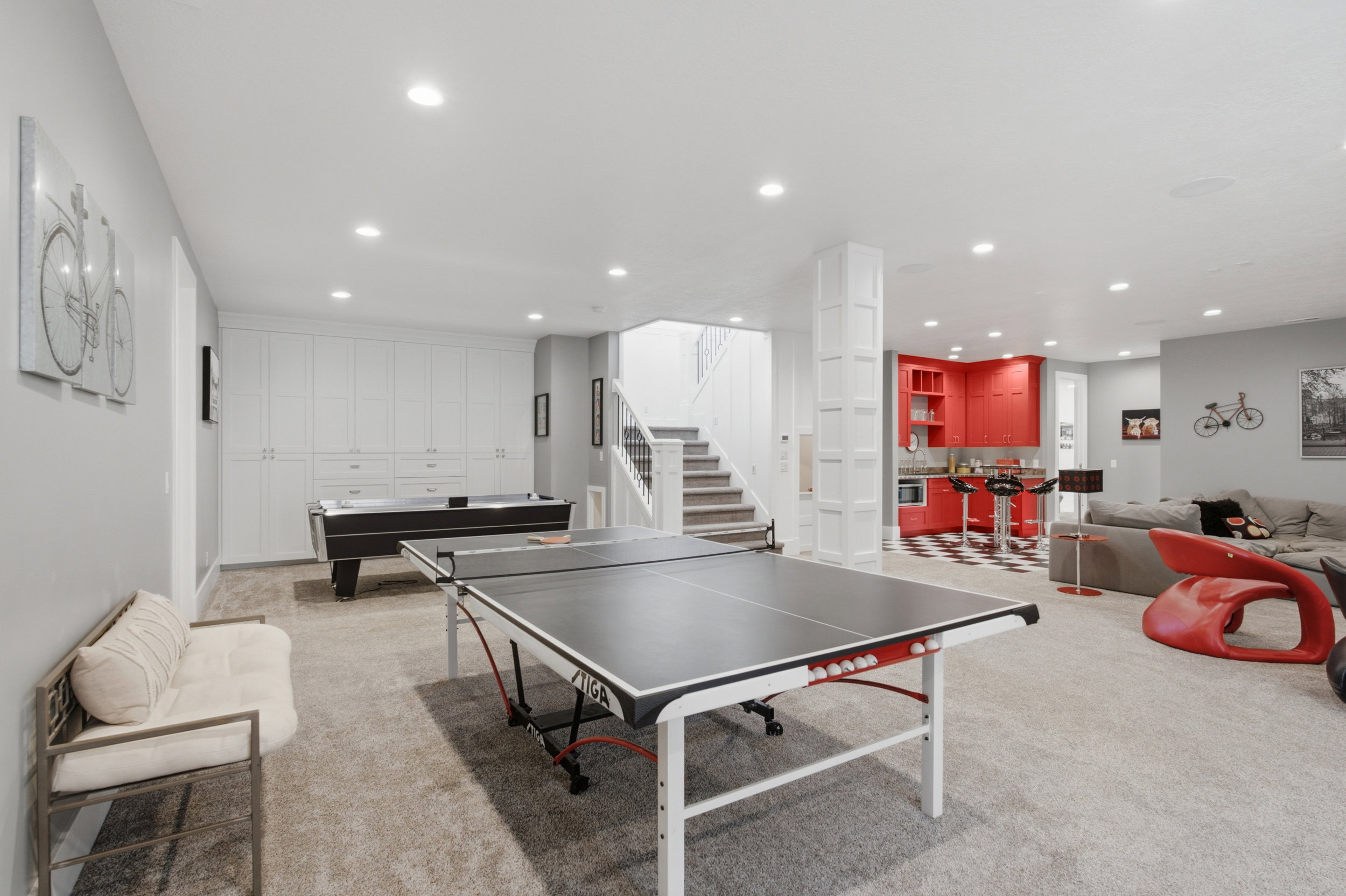 Spacious lower-level area with recessed lighting, light-toned carpeting, and a staircase with white risers