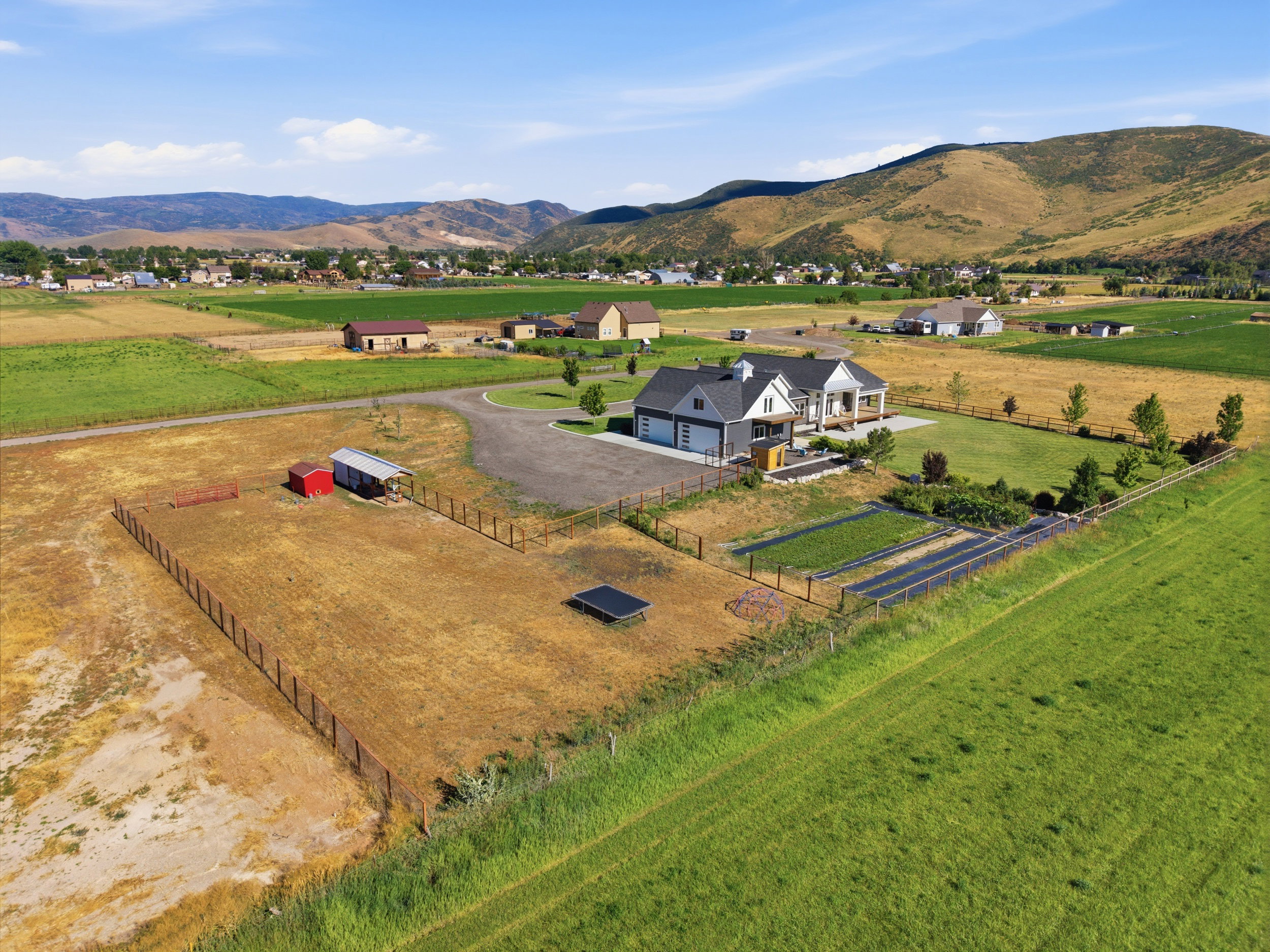 Expansive rural property featuring a contemporary residence with an attached garage, a large fenced garden area, and a separate fenced pasture