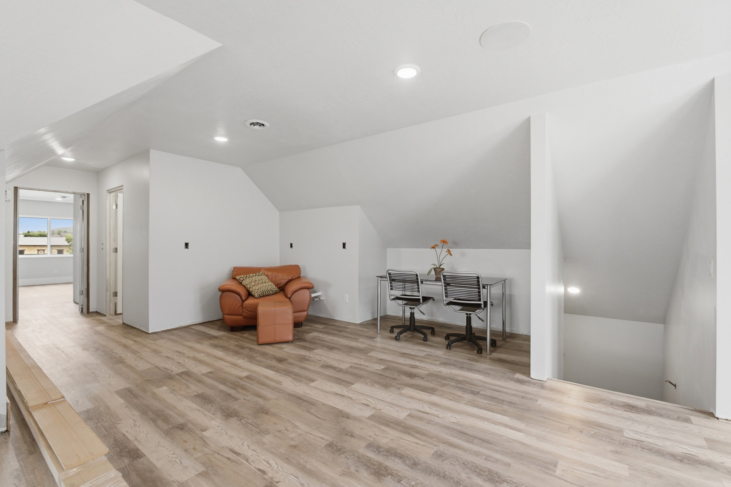 Spacious loft area featuring wood-finish flooring, recessed lighting, and a built-in ceiling speaker