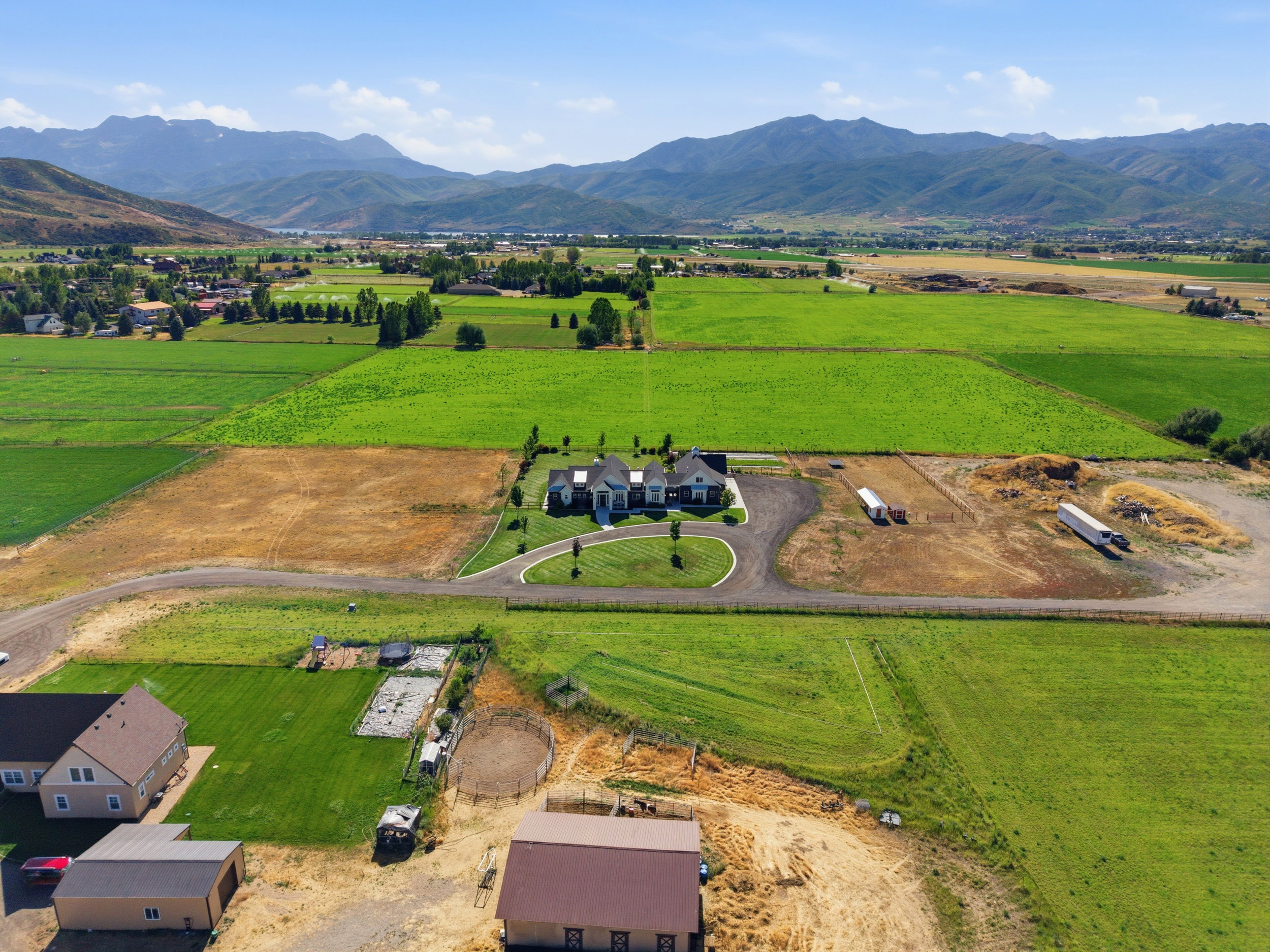 Expansive aerial landscape featuring a large residence with a circular drive, surrounded by cultivated fields