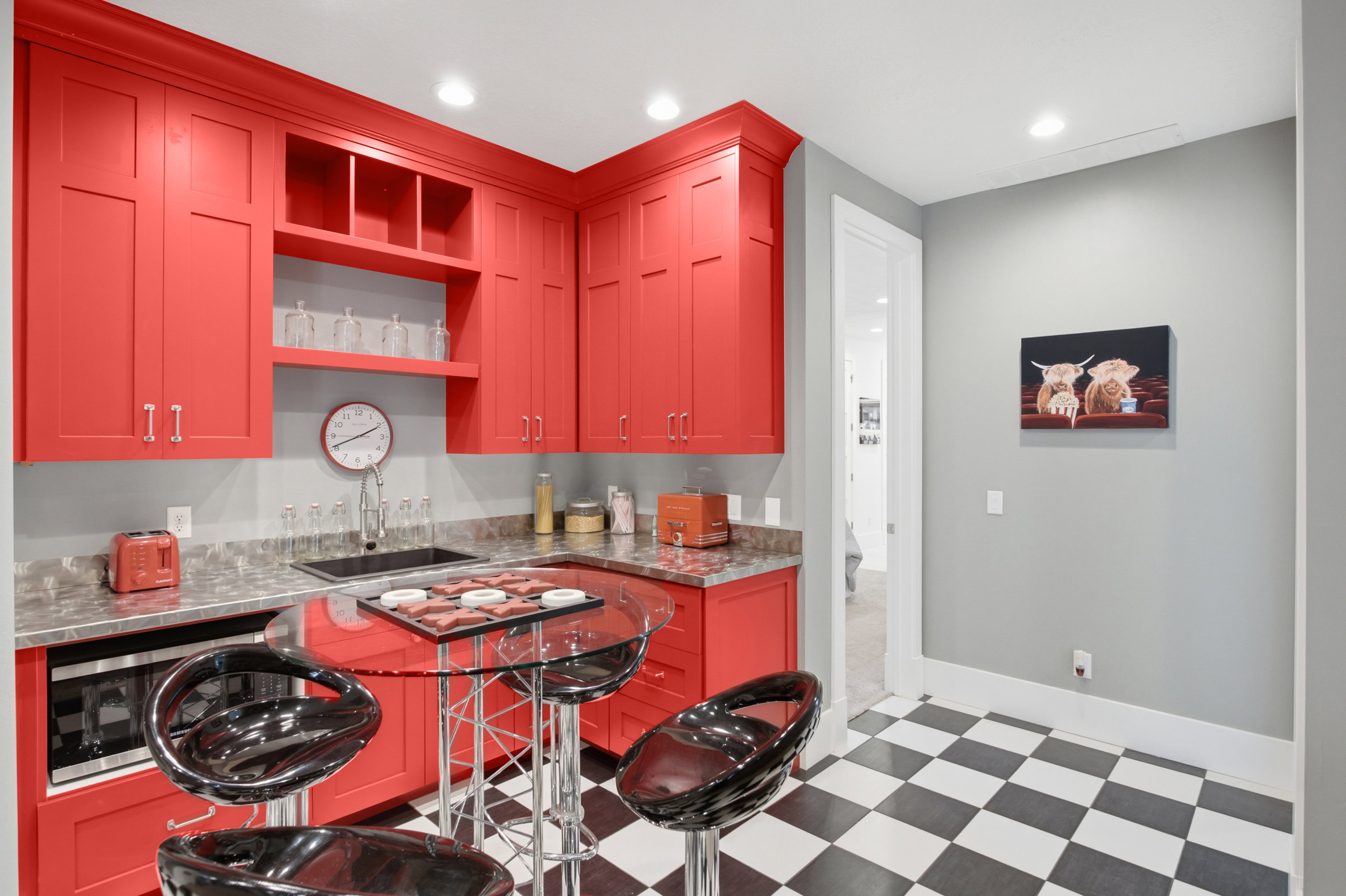 Compact kitchen area featuring vibrant red cabinetry, a built-in microwave, and a black and white checkerboard floor