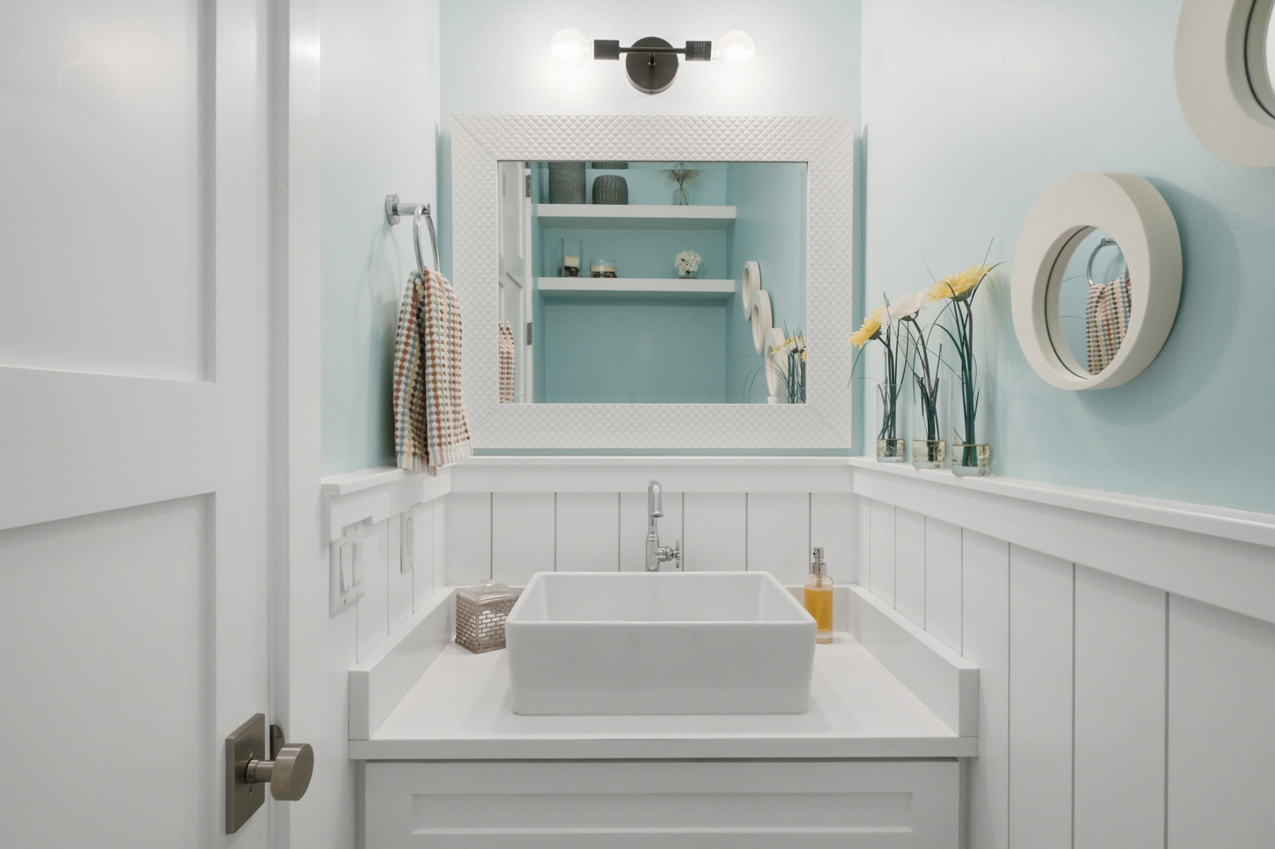 Powder room featuring board and batten wainscoting, a rectangular vessel sink, and a framed mirror