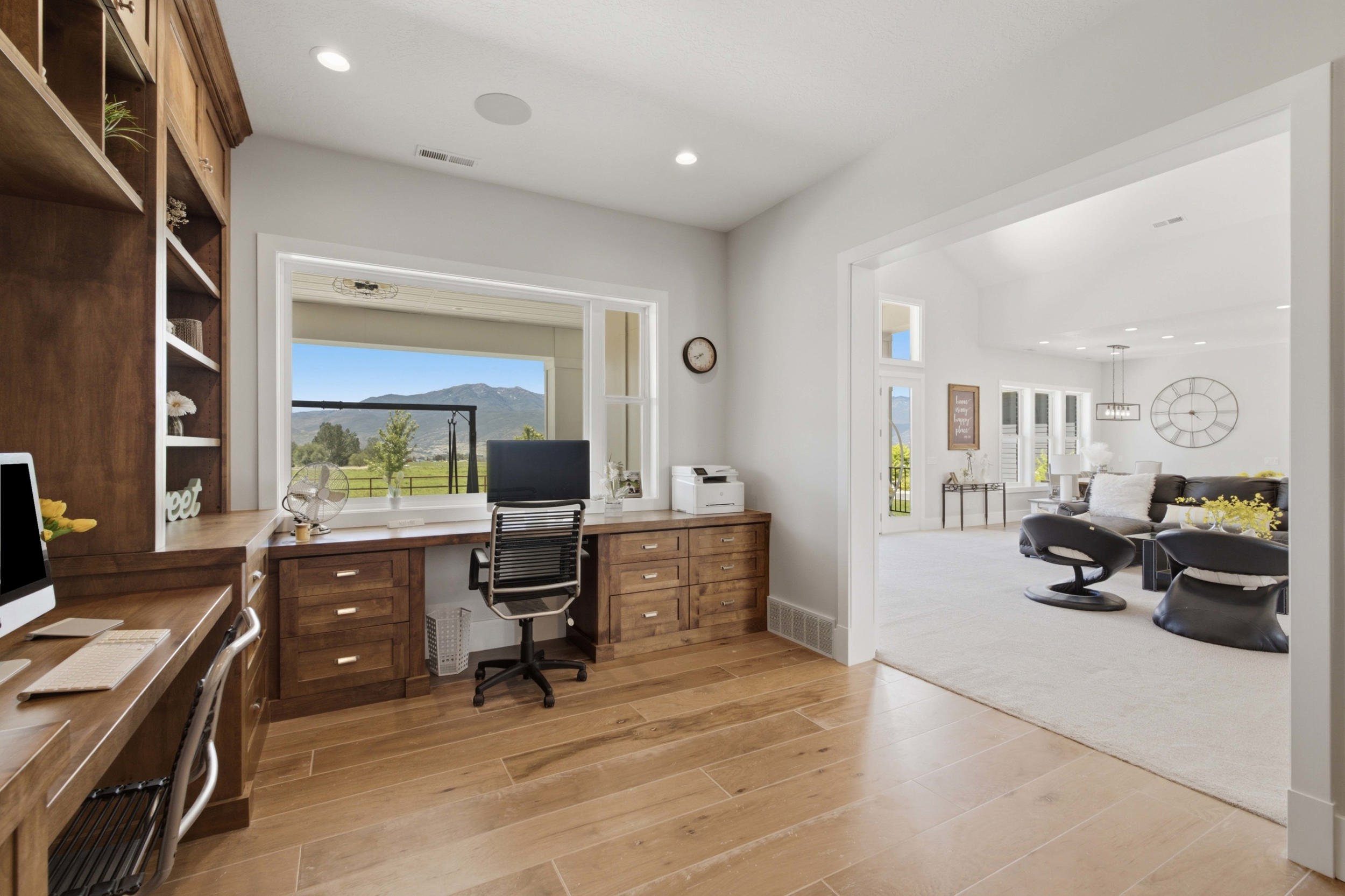 Built-in custom cabinetry with shelving, expansive window offering mountain scenery, wood-finish flooring, recessed lighting, and a wide entryway to another living space