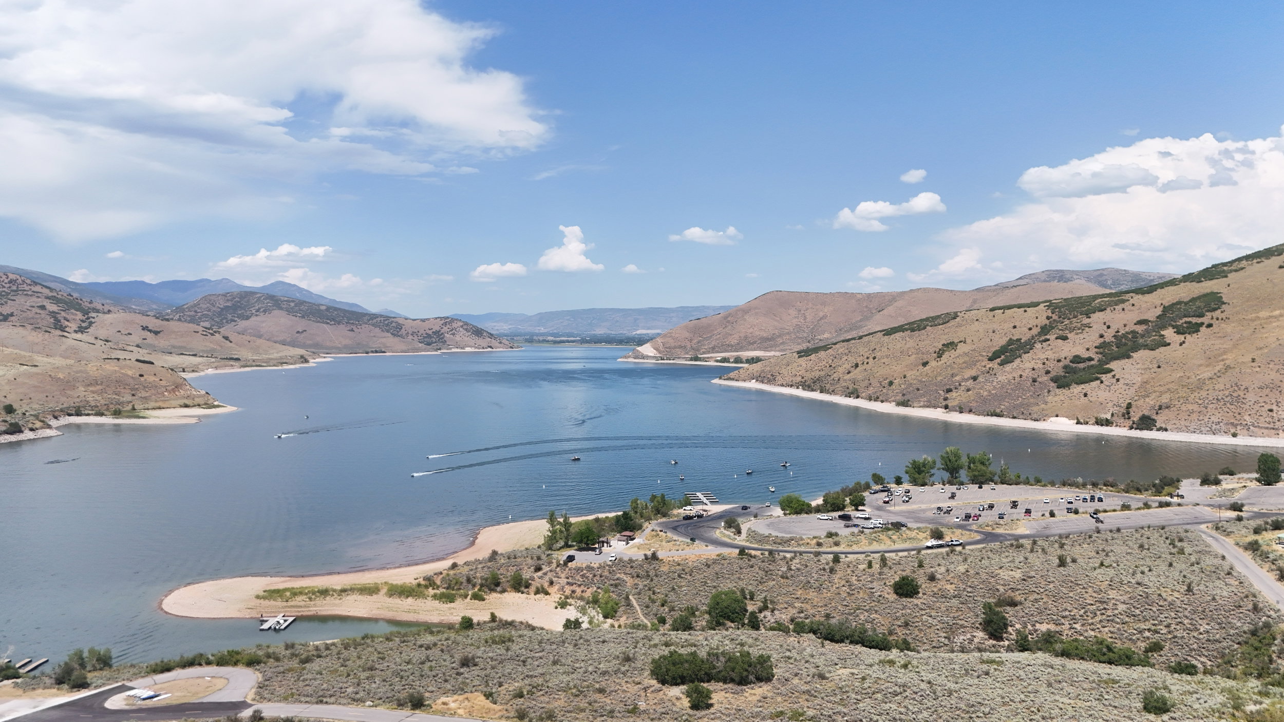 Expansive lake surrounded by rolling hills under a bright sky