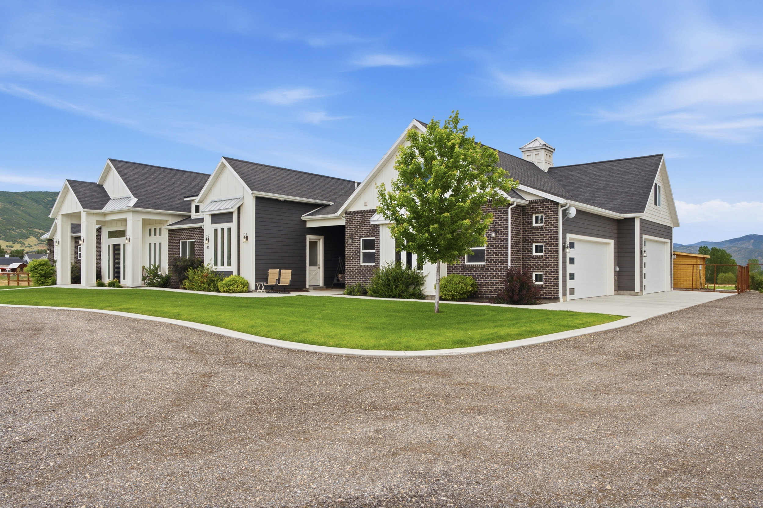 Contemporary residence featuring dark siding, white trim, and brick accents