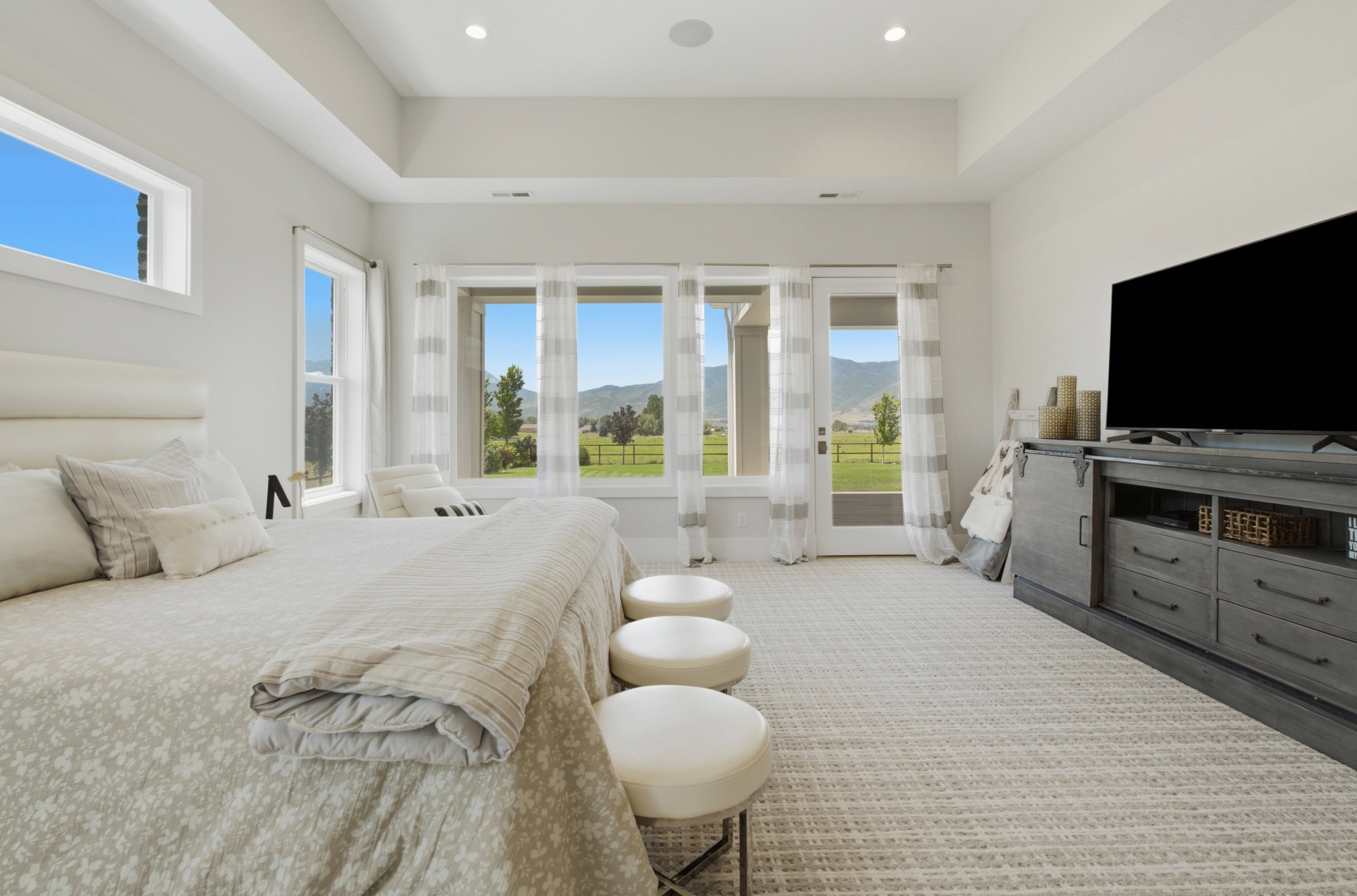 Spacious room featuring multiple windows, a tray ceiling with recessed lighting, and light-colored patterned carpeting