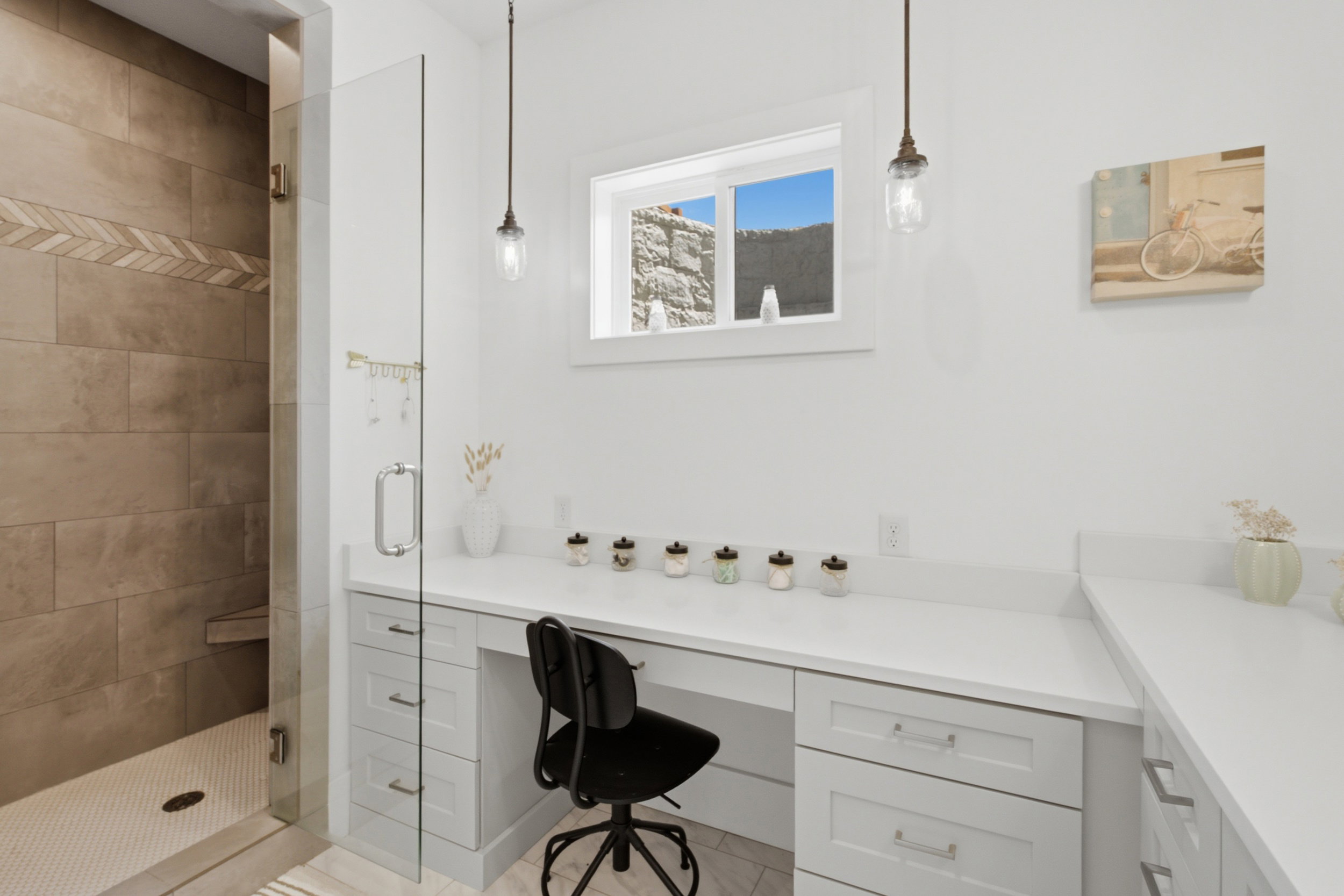 Built-in vanity with light grey shaker-style cabinetry, white countertops, and a clear glass shower enclosure
