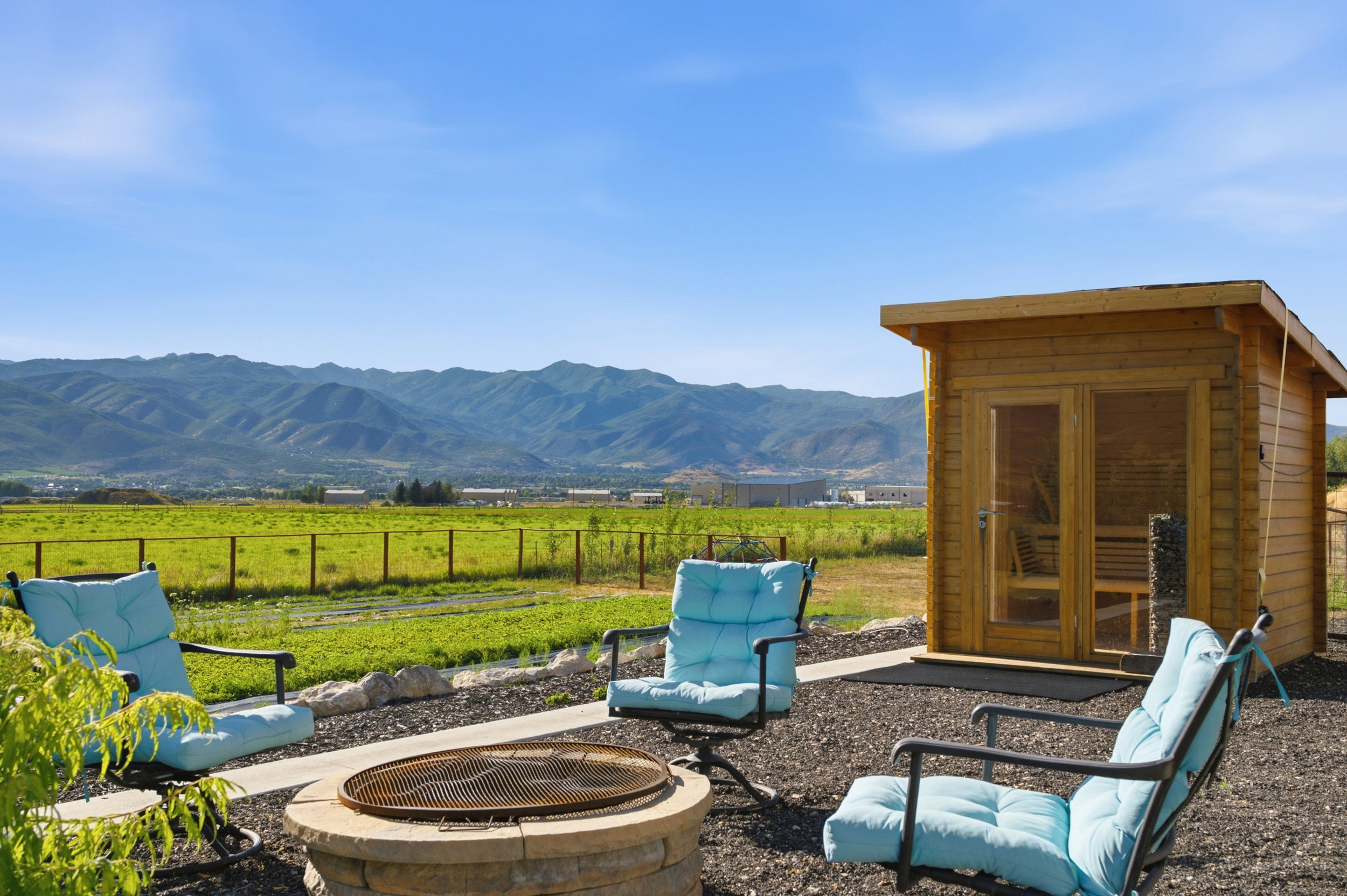 Outdoor sauna with double glass doors and a stone fire pit area