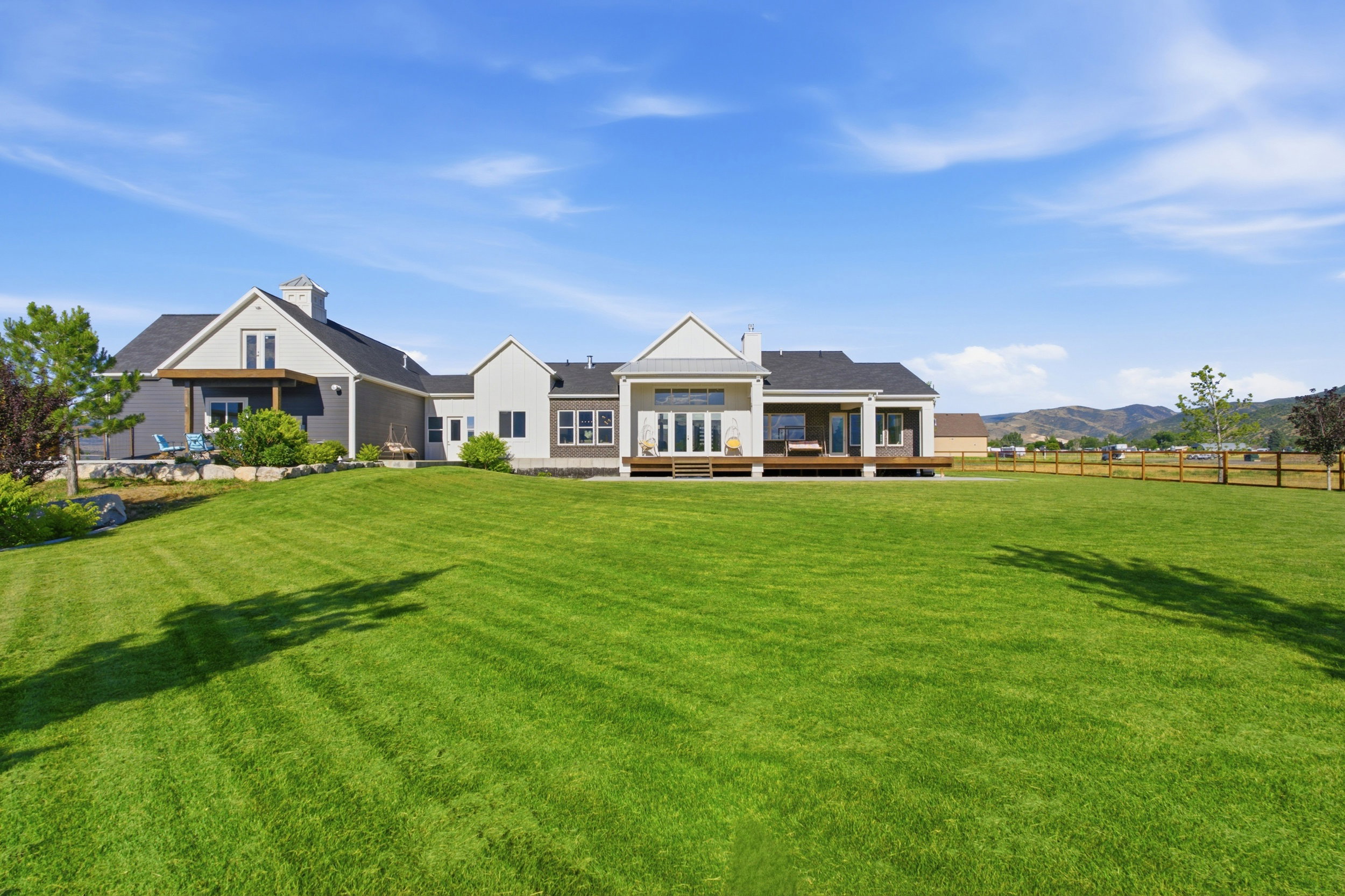 Expansive backyard featuring a manicured lawn, multiple outdoor decks, and mountain scenery