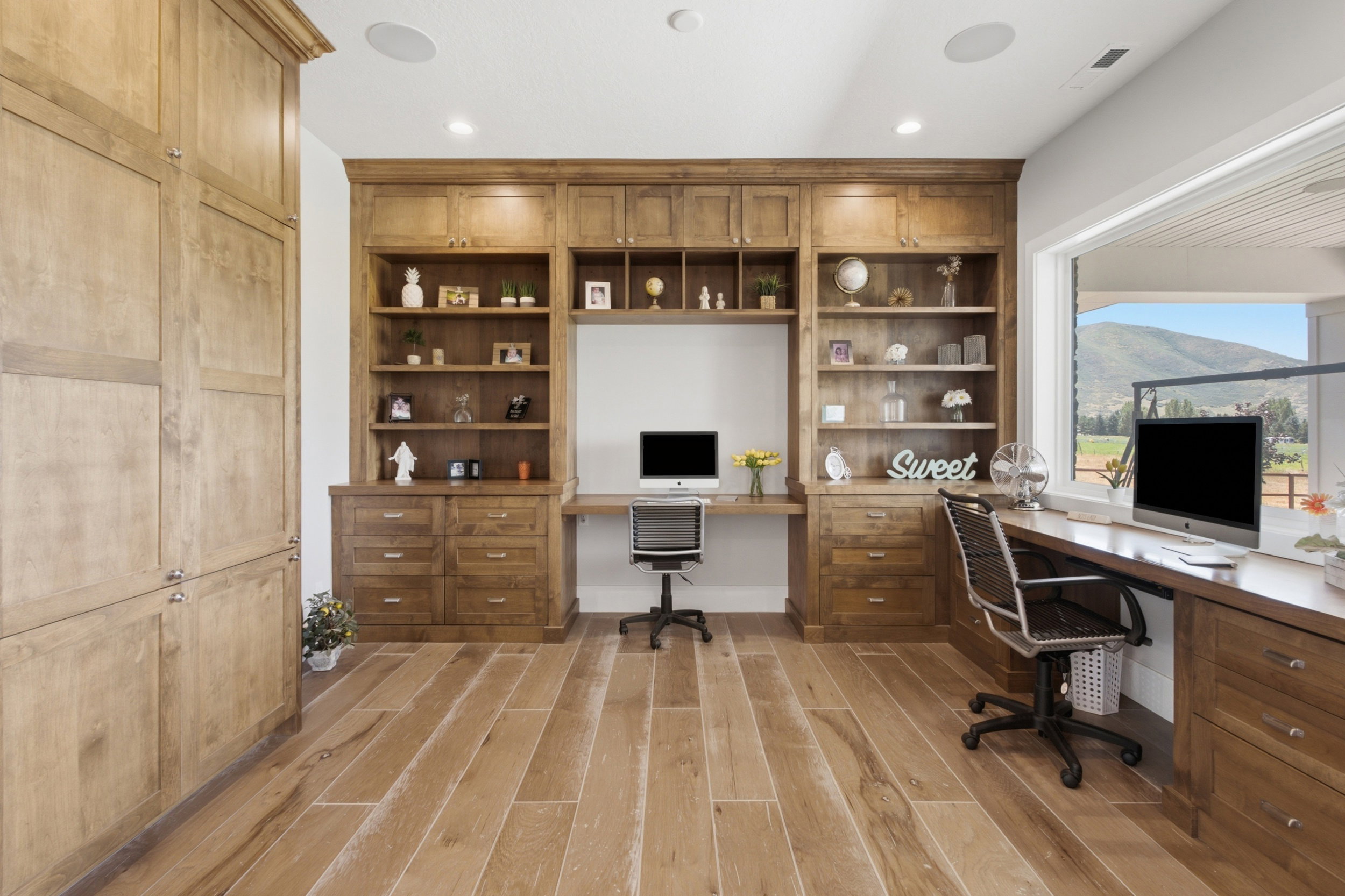 Custom built-in cabinetry with integrated desks, hardwood-style flooring, recessed lighting, and expansive window with mountain scenery