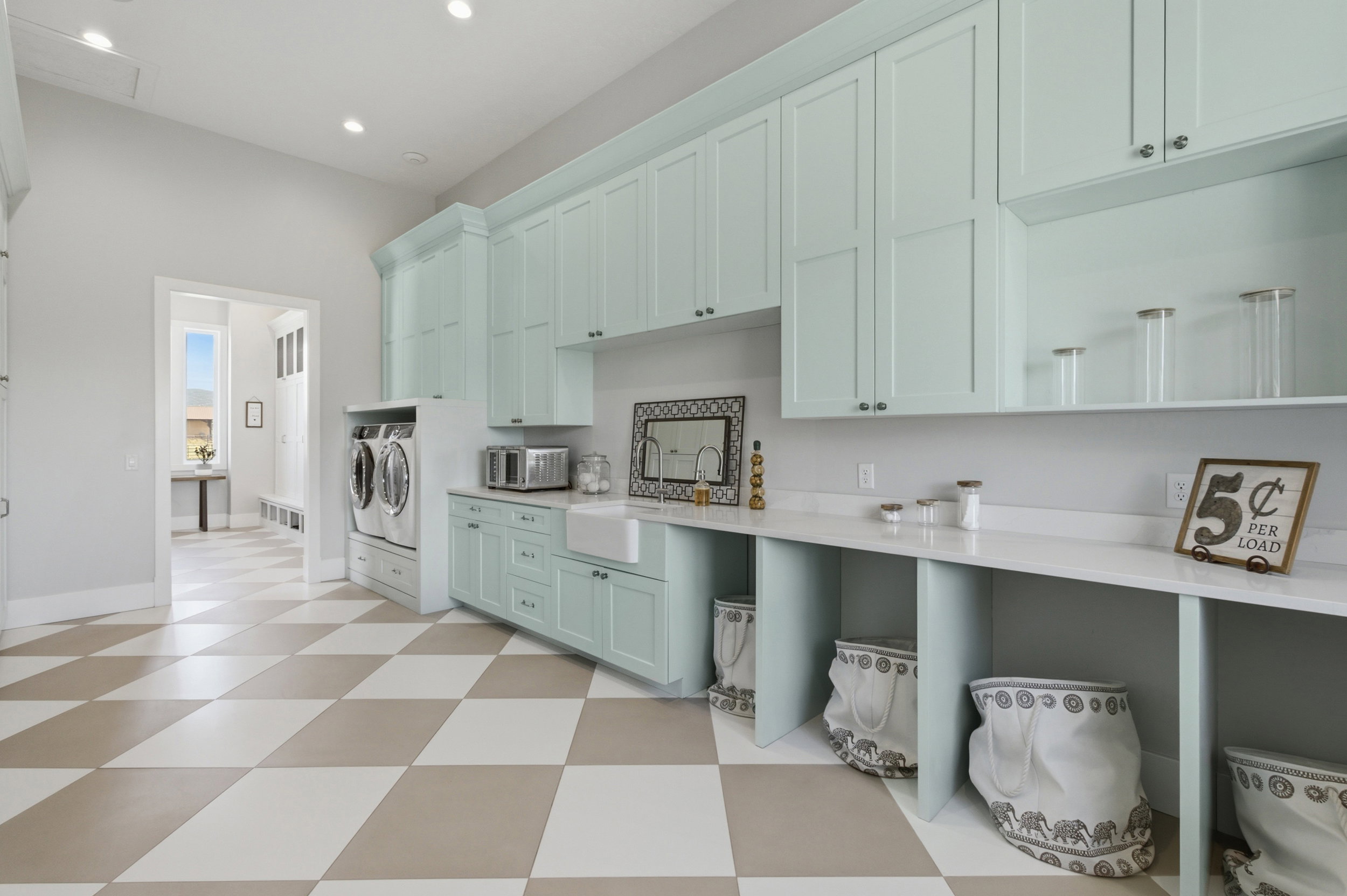 Laundry room featuring extensive light blue cabinetry, built-in utility sink, and white countertops