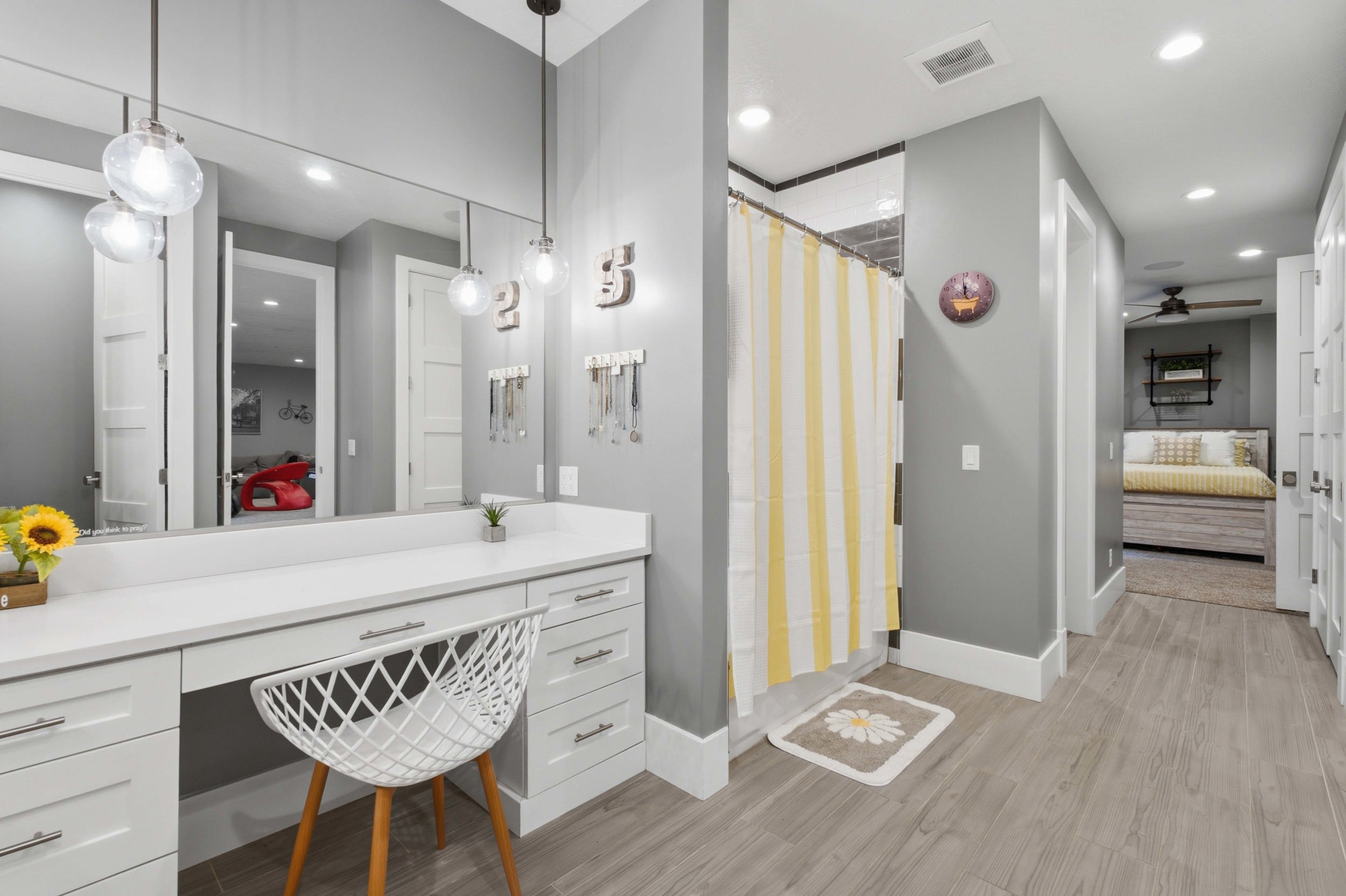 Bathroom featuring a vanity with white cabinetry, a large mirror, and two pendant light fixtures