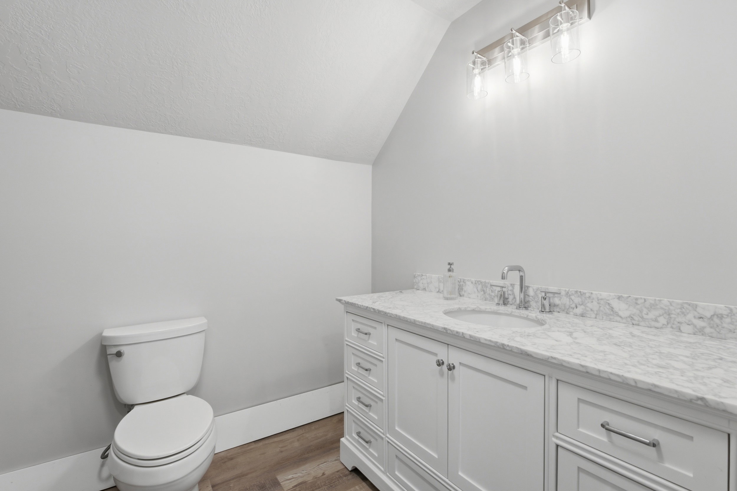 Bathroom featuring a white vanity with a stone-finish countertop, undermount sink, and brushed nickel hardware