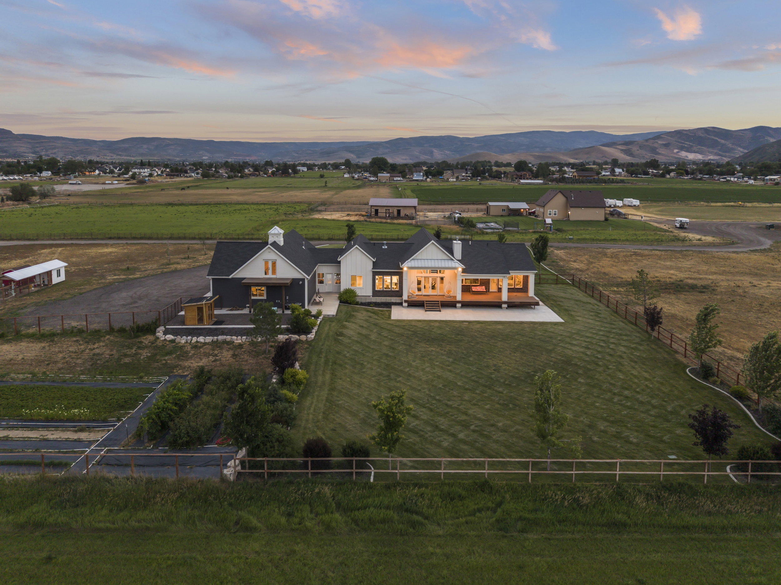 Expansive property featuring a modern farmhouse-style residence with a dark facade, light-colored accents, and a prominent covered porch