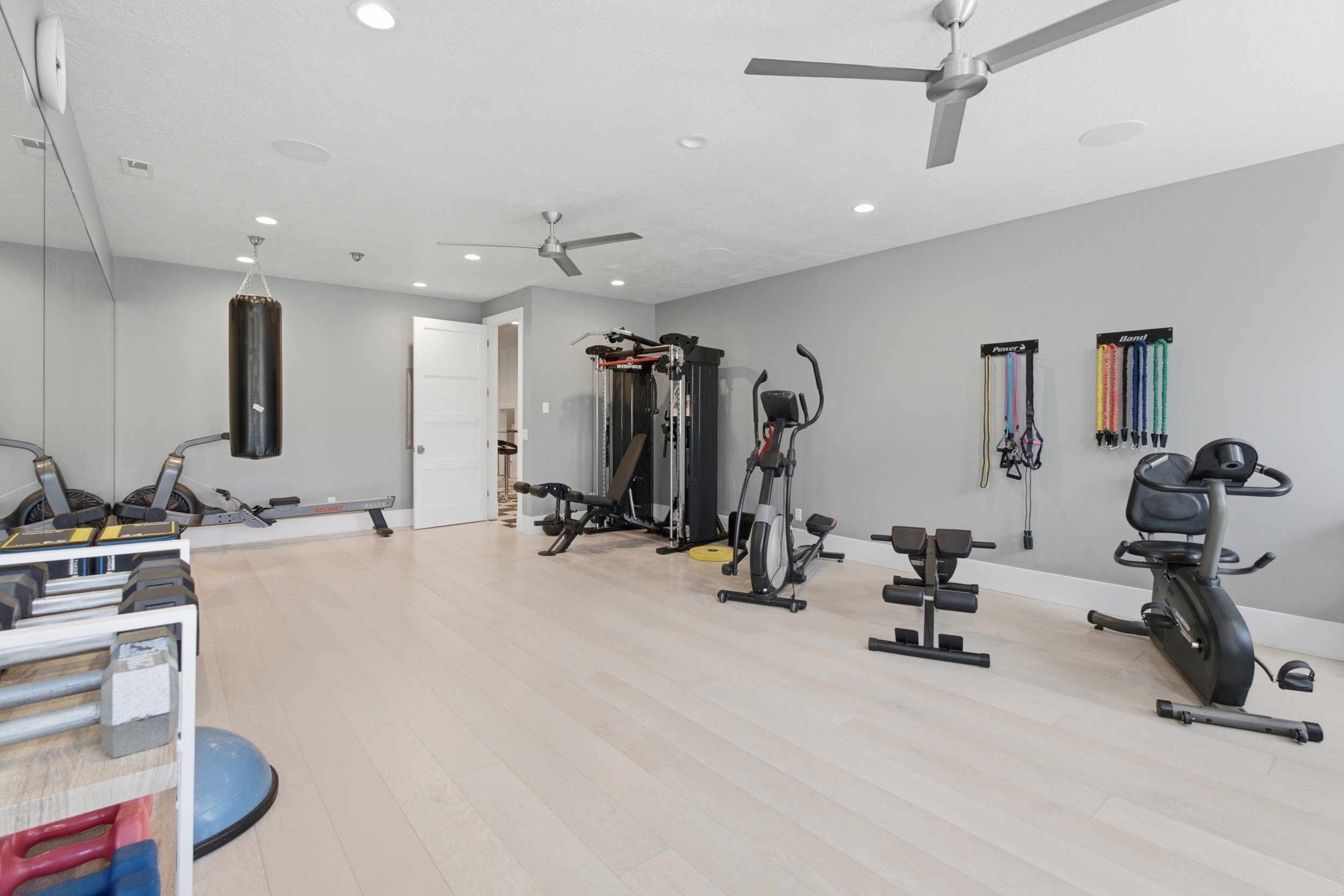 Spacious interior room featuring light wood-finish flooring, recessed lighting, and two ceiling fans