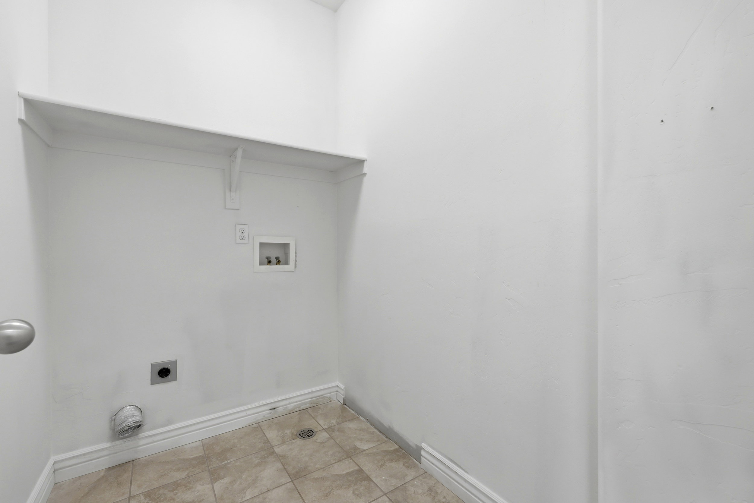 Dedicated laundry area with tile flooring and a built-in wall shelf