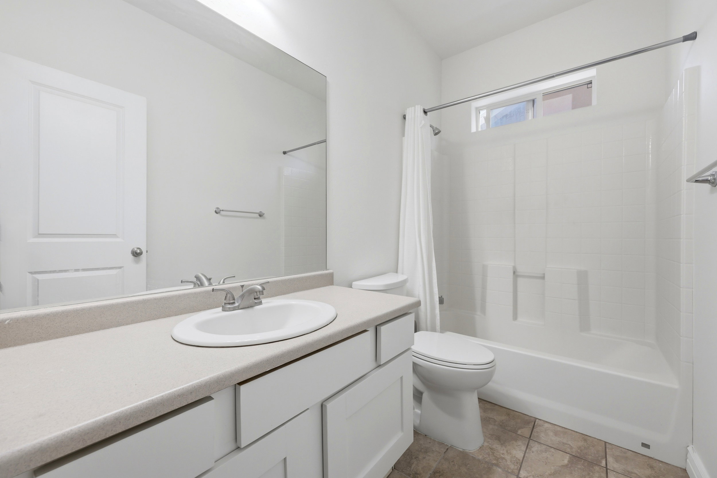 Bathroom featuring a white vanity with an integrated sink, a light-toned countertop, and white cabinetry