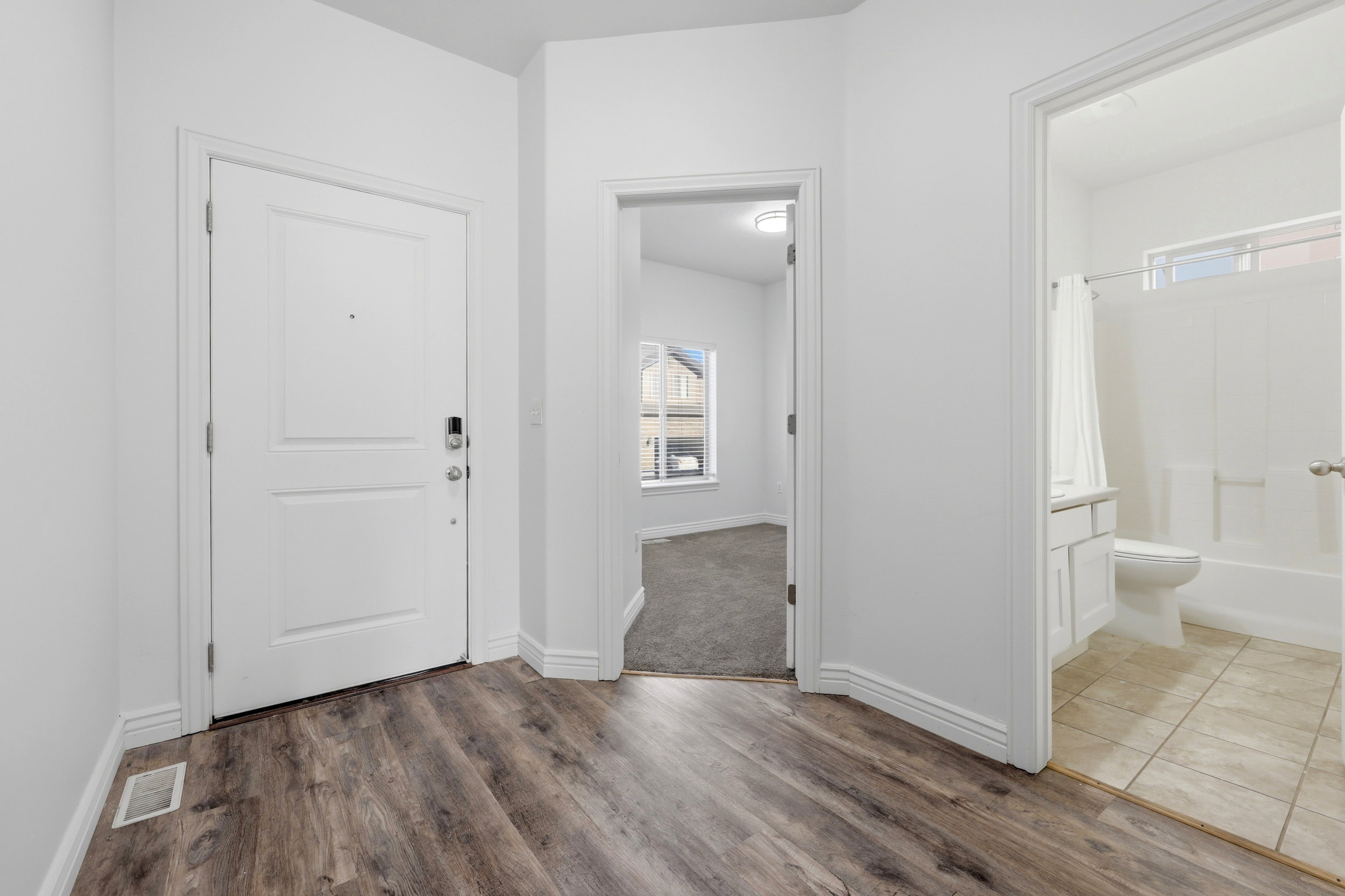 Entryway featuring wood-finish flooring, a white paneled door with a smart lock, and white baseboards