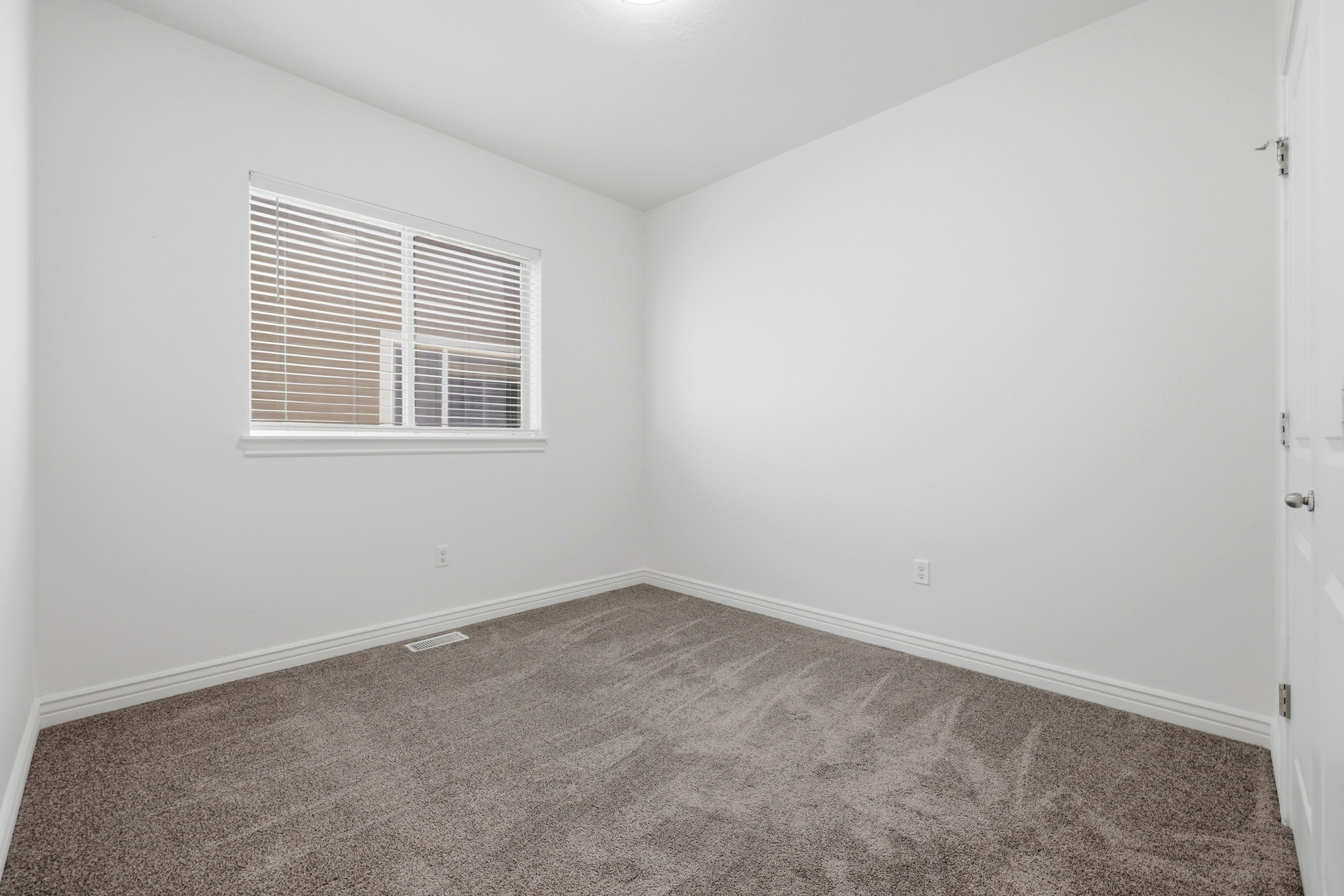Room featuring a neutral color palette, plush carpet, white baseboards, and a window with blinds