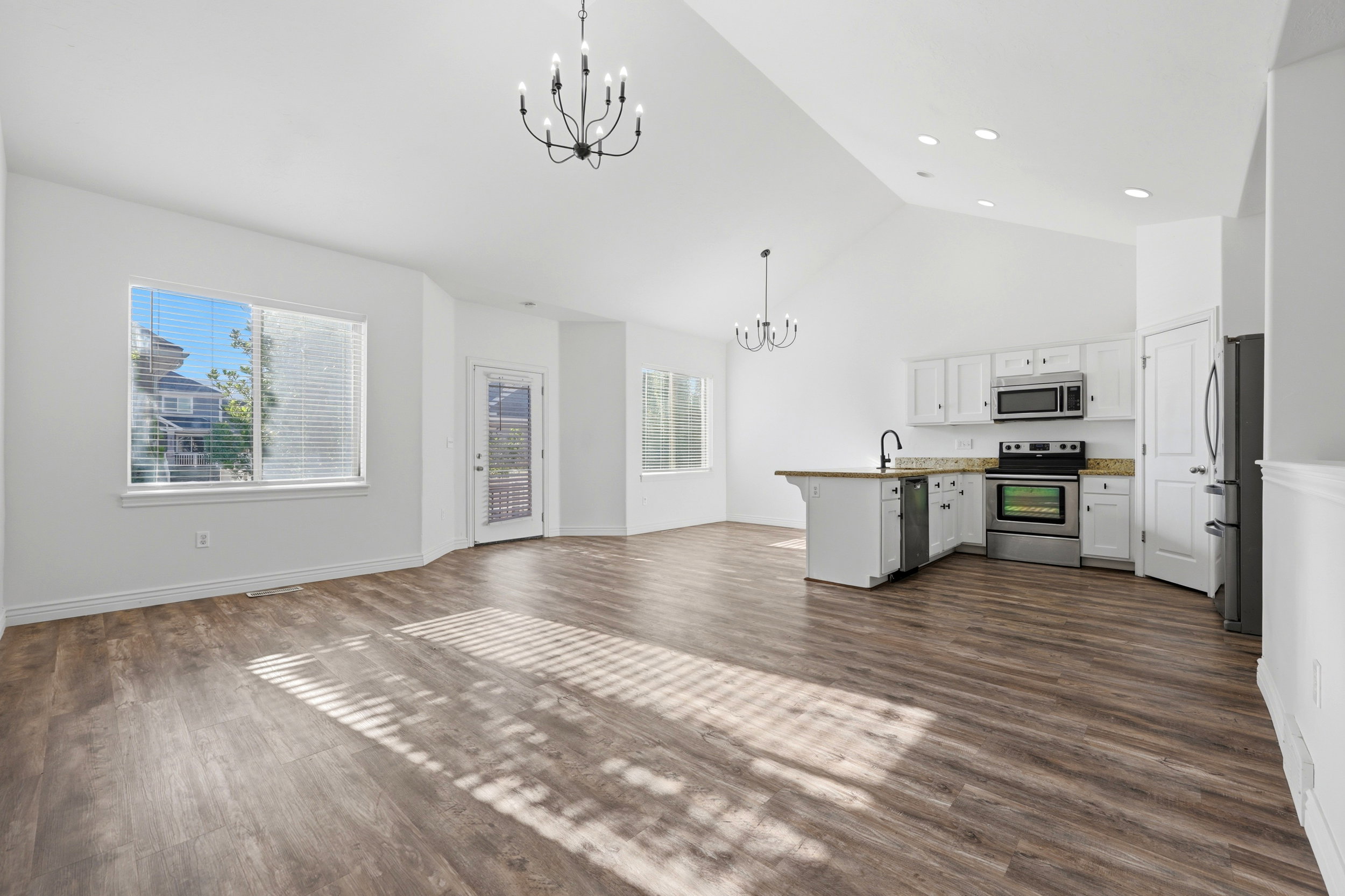 Open-concept living area featuring vaulted ceilings, wood-finish flooring, and a modern kitchen